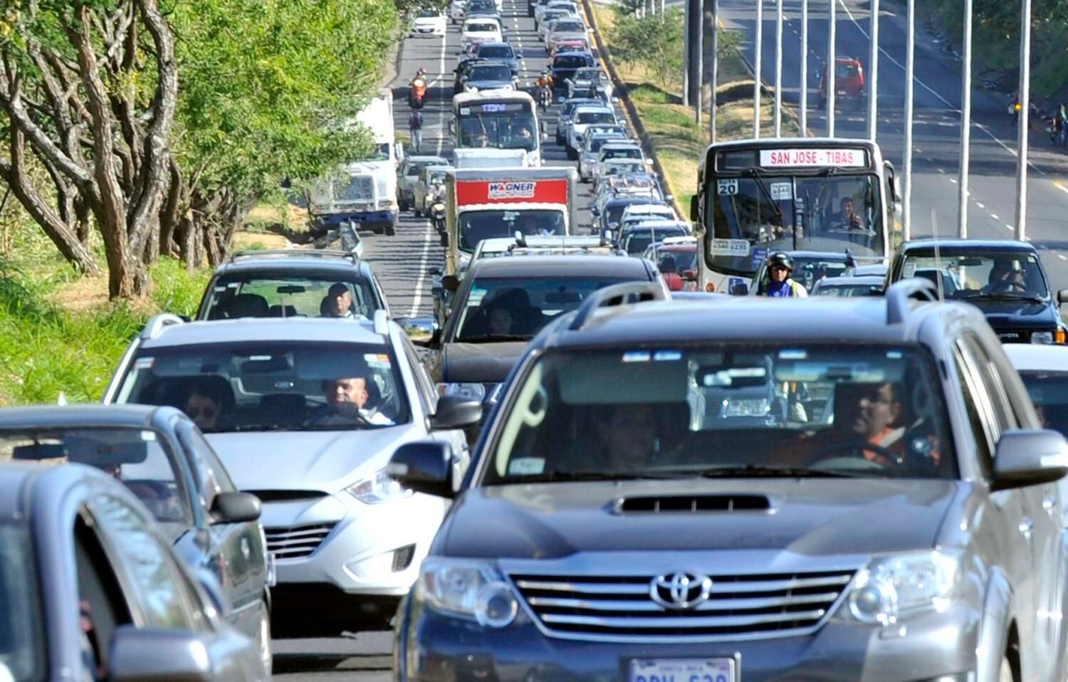 Tráfico denso con buses y vehículos en ruta hacia San José, en el contexto del aumento del deducible del seguro voluntario de automóviles del INS por alta siniestralidad y encarecimiento de repuestos.