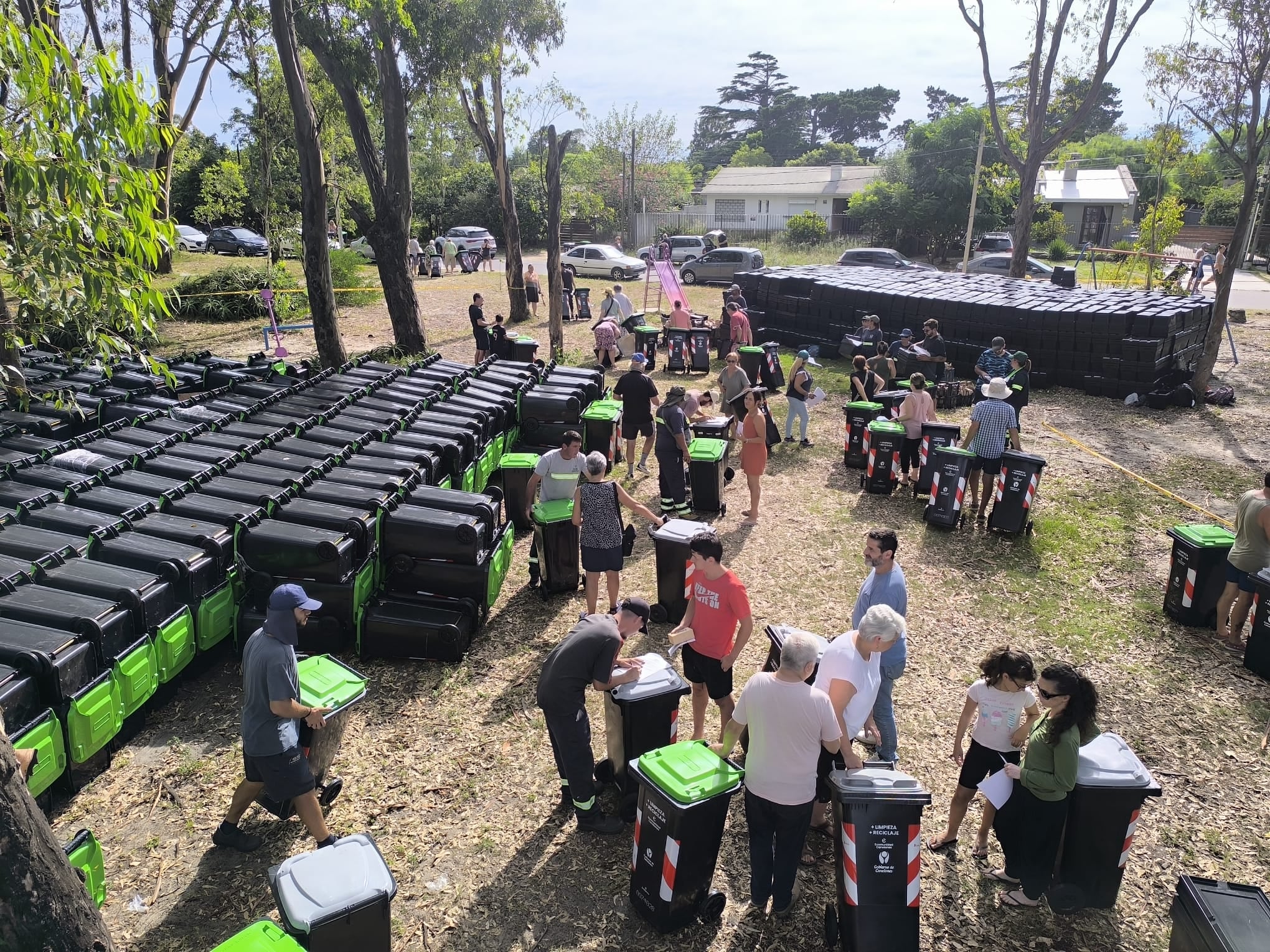 Un grupo de personas recibe basureros en un parque.