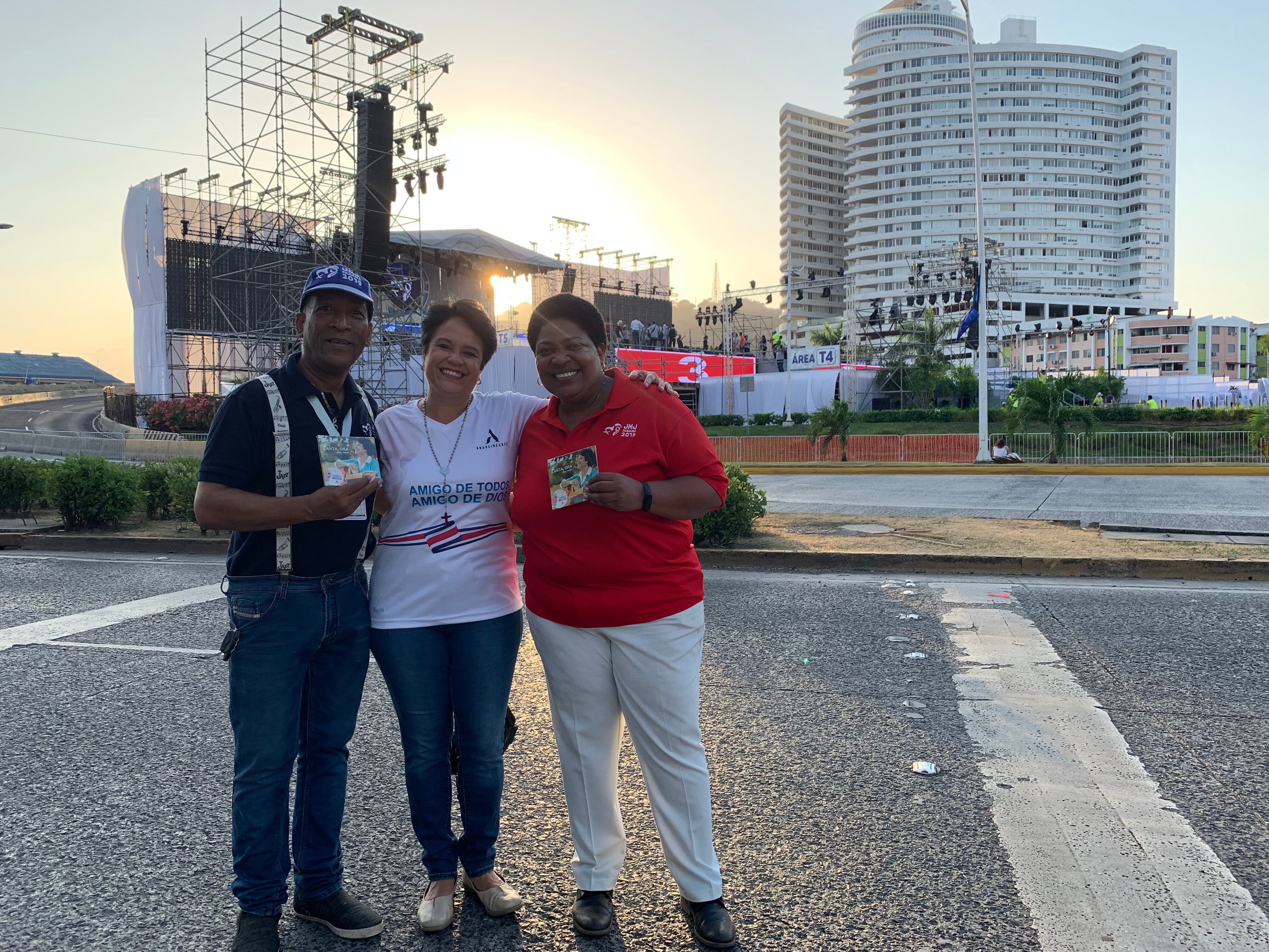 Tres personas juntas y sonrientes saluda a la cámara de pie