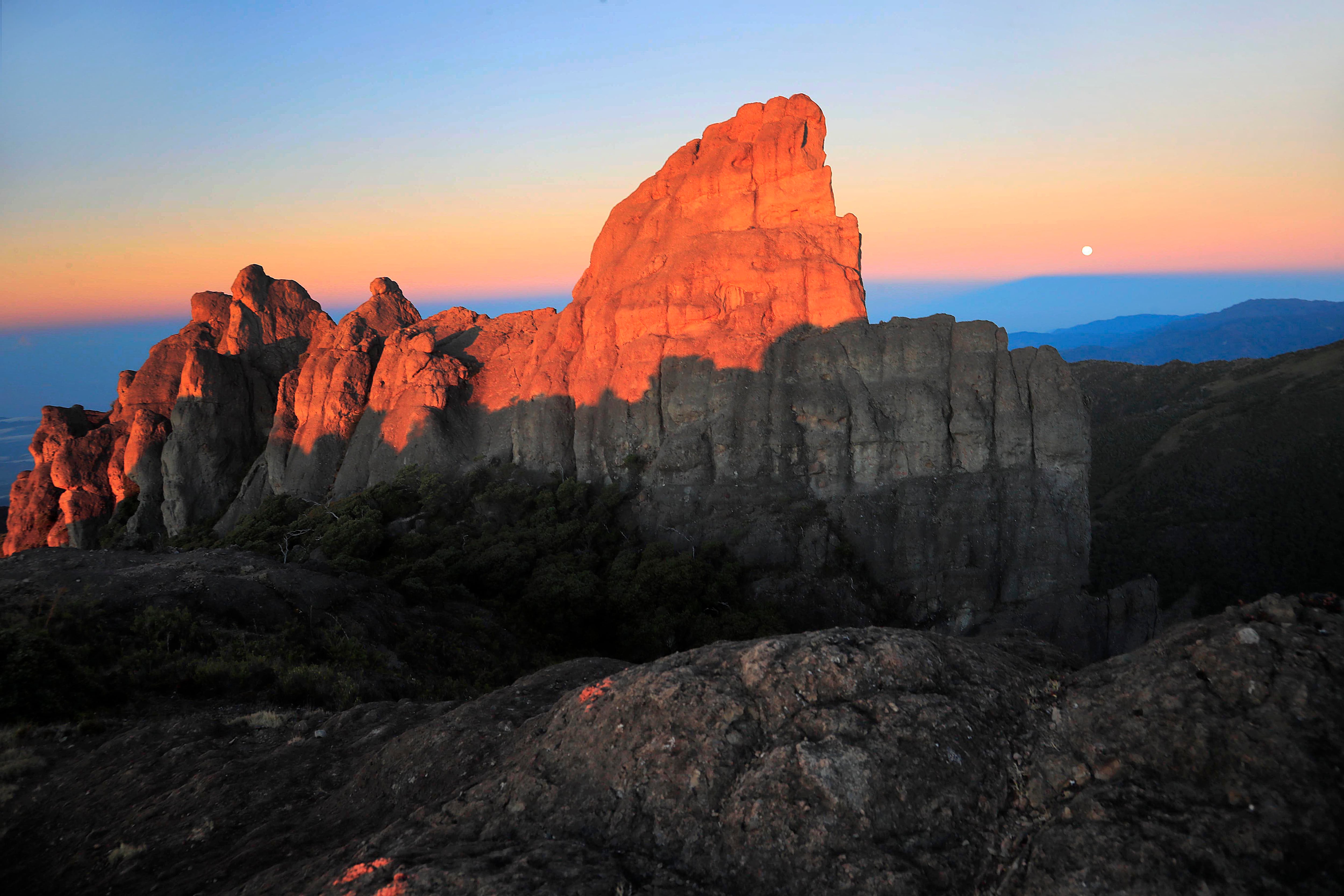 24/02/2024 Parque Nacional Chirripó: Los primeros rayos del sol tiñen de dorado los simbólicos Crestones. Al fondo la luna llena empieza su despedida sobre los tonos pastel del celaje de amanecer. Todo un espectáculo a las 5:43 a.m. Foto: Rafael Pacheco Granados