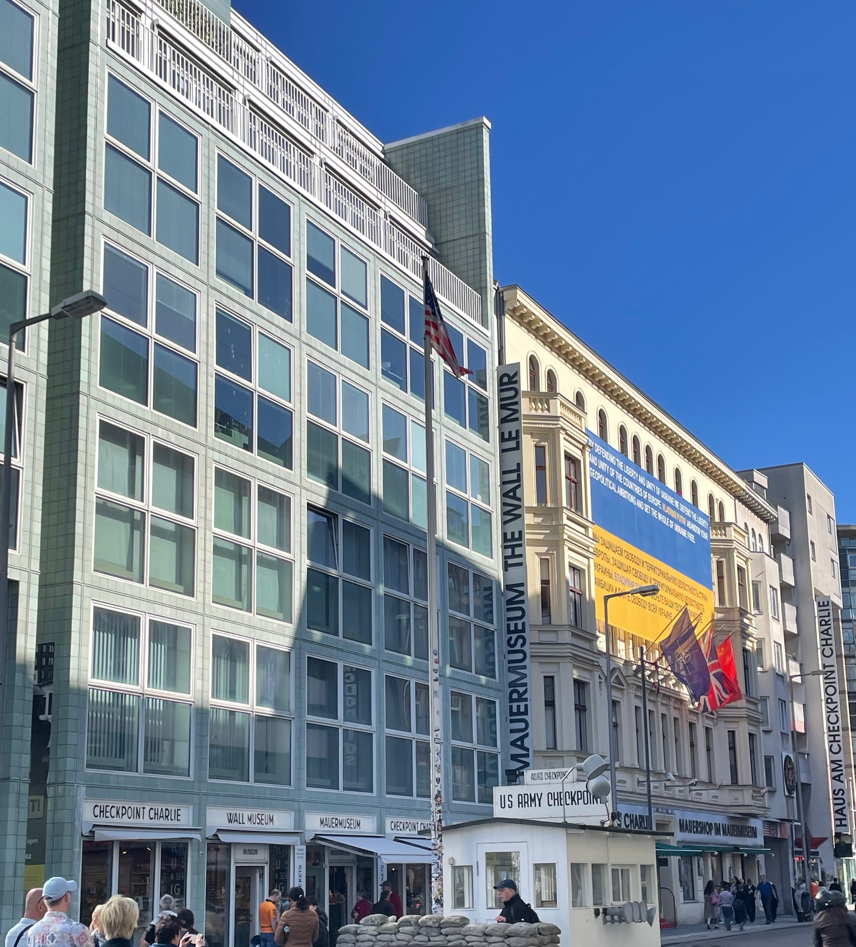 Checkpoint Charlie, antigua división de las zonas de Berlín, y una bandera de Ucrania con mensajes alusivos a la defensa de Europa.