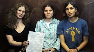 Las integrantes de Pussy Riot, de izquierda a derecha, Maria Alekhina, Yekaterina Samutsevich y Nadezhda Tolokonnikova, muestran un veredicto del tribunal mientras están sentadas en una jaula de cristal en una sala del tribunal en Moscú, el 17 de agosto de 2012.