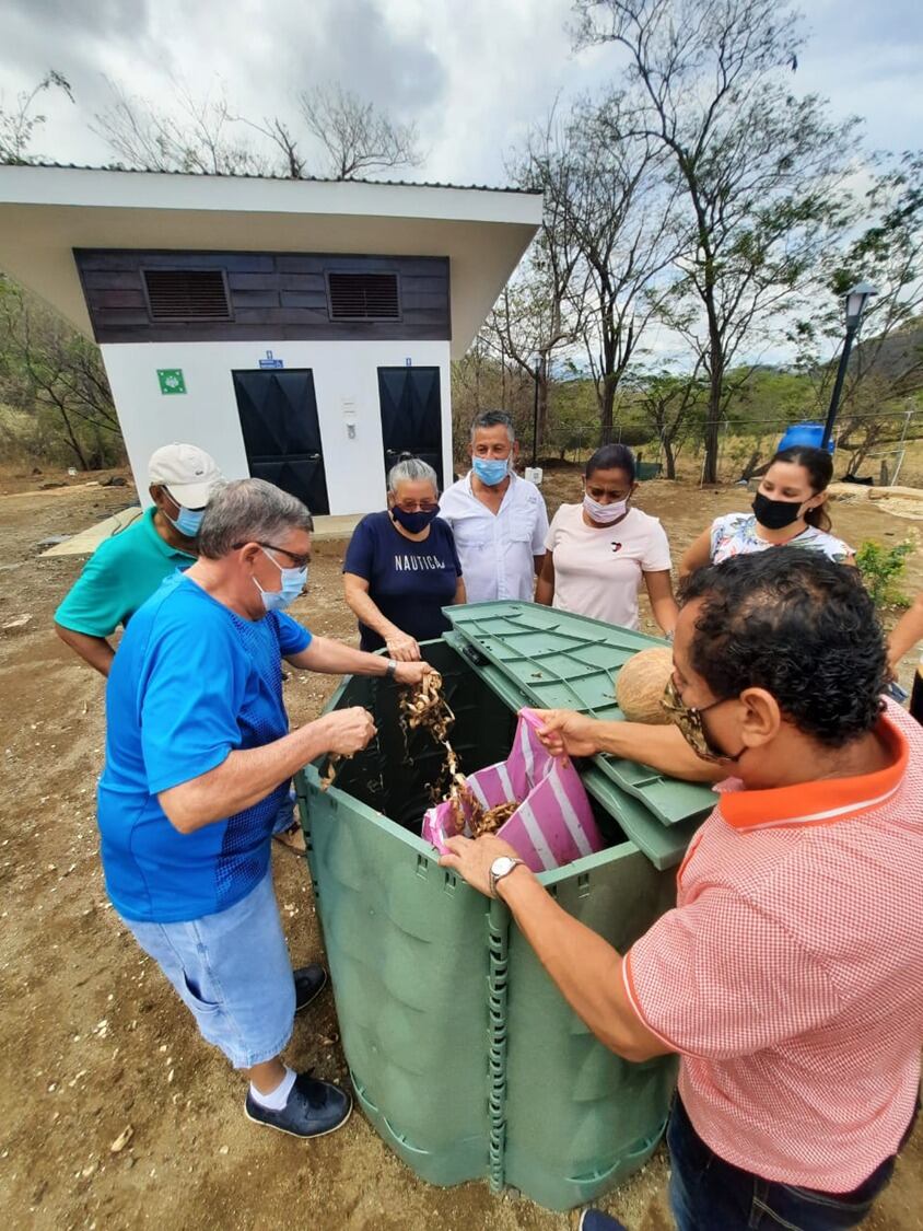 Un grupo de personas con una compostera comunitaria.