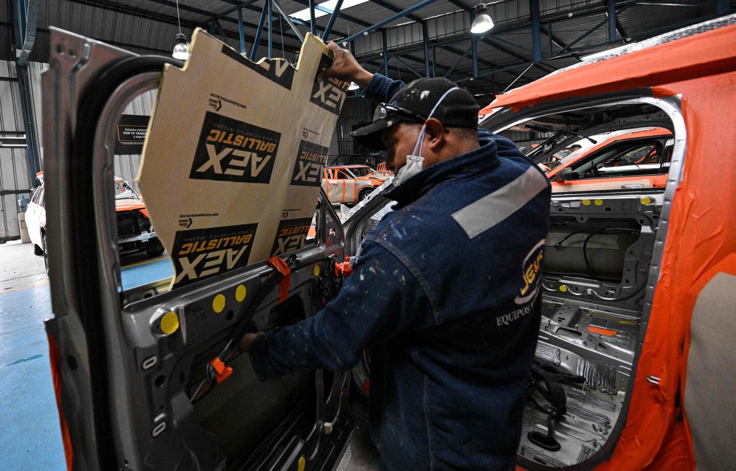 A mechanic works to bulletproof a vehicle at the Auto Express security company's workshop in Quito on August 15, 2023. Owners of high-end vehicles pay fortunes to bulletproof them against drug trafficking and gang violence, amid a "boom" in Ecuador's security industry. (Photo by MARTIN BERNETTI / AFP)