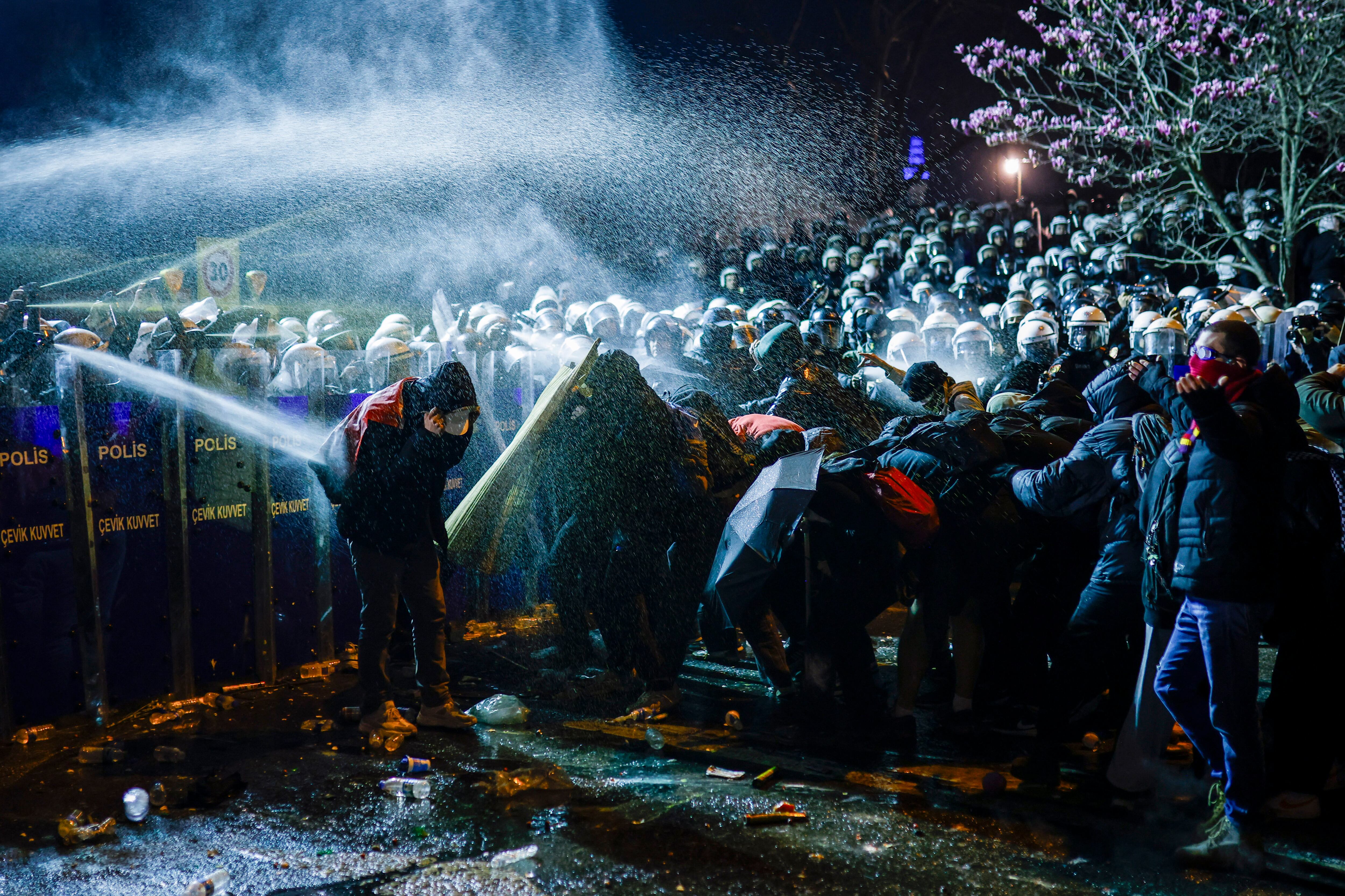 Manifestantes se protegen mientras la policía antidisturbios turca les lanzaba gases lacrimógenos durante una manifestación frente al ayuntamiento de Estambul en apoyo al alcalde local. Fotografía: