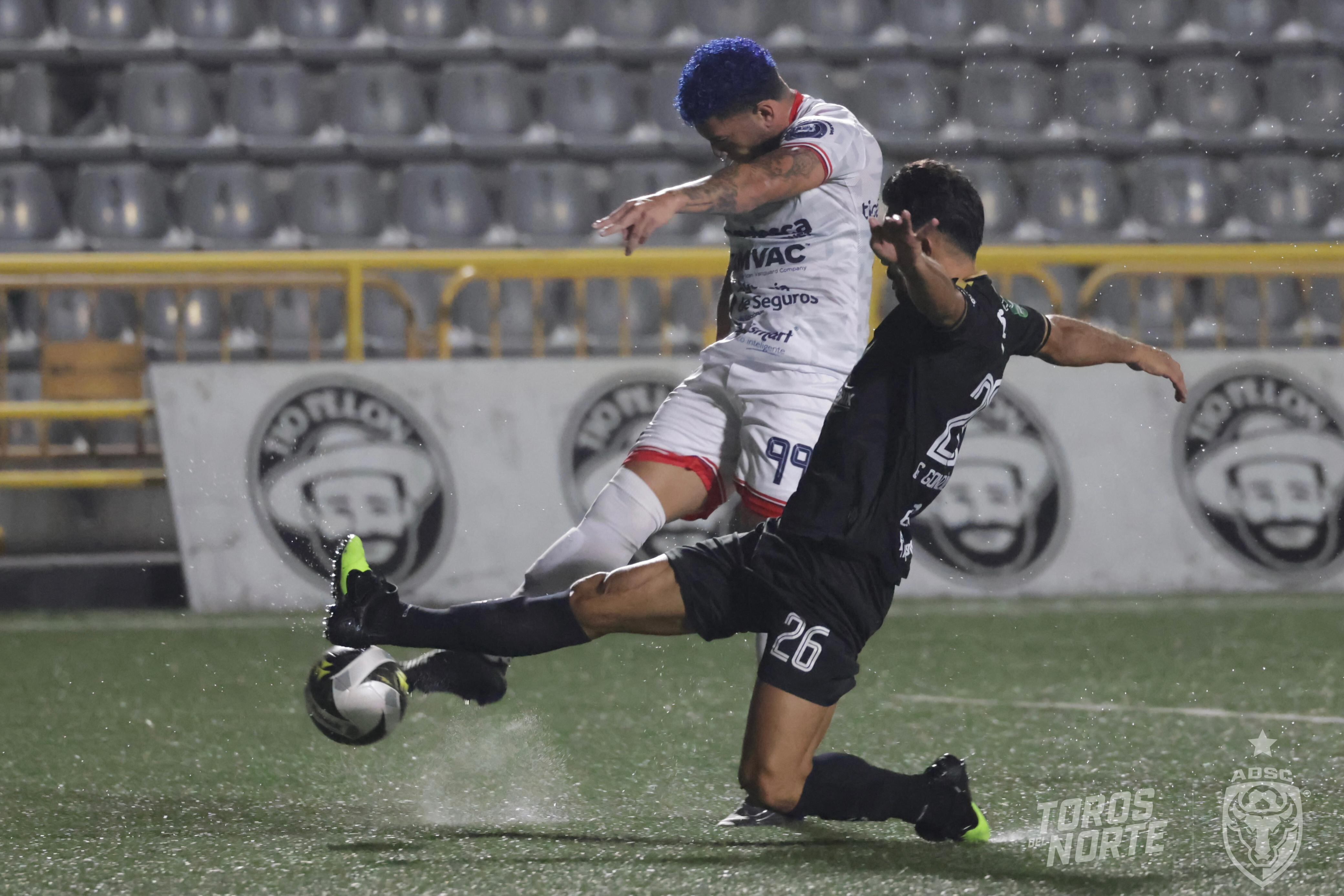 El atacante de San Carlos Brian Martínez (izquierda) marco el primer gol del juego, pese al esfuerzo del defensor del Sporting FC, Giancarlo González.