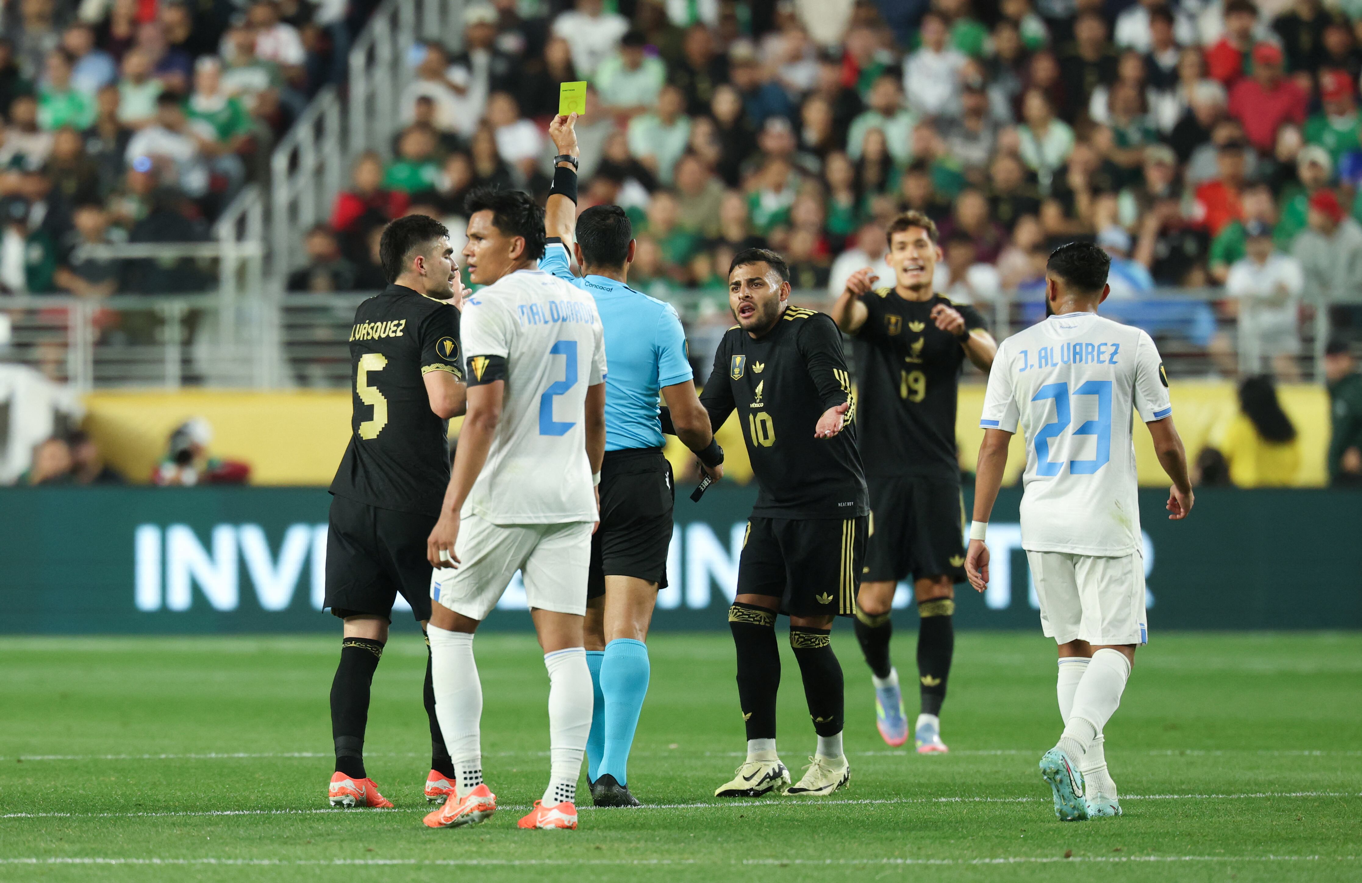 Los jugadores discuten mientras el árbitro Juan Gabriel Calderón amonesta al defensa mexicano Julián Araujo