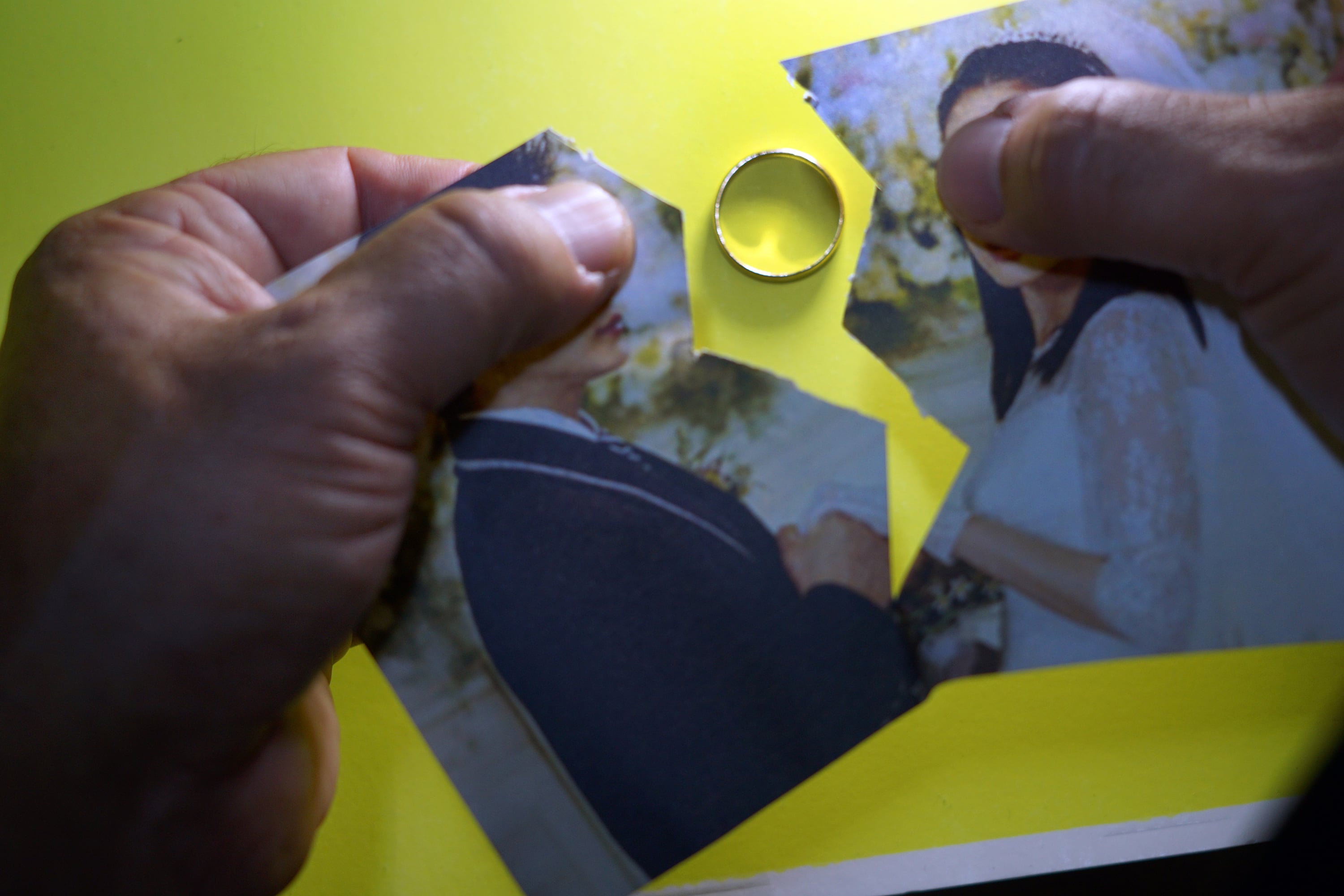 Un par de manos rompe una foto de una pareja contrayendo matrimonio.