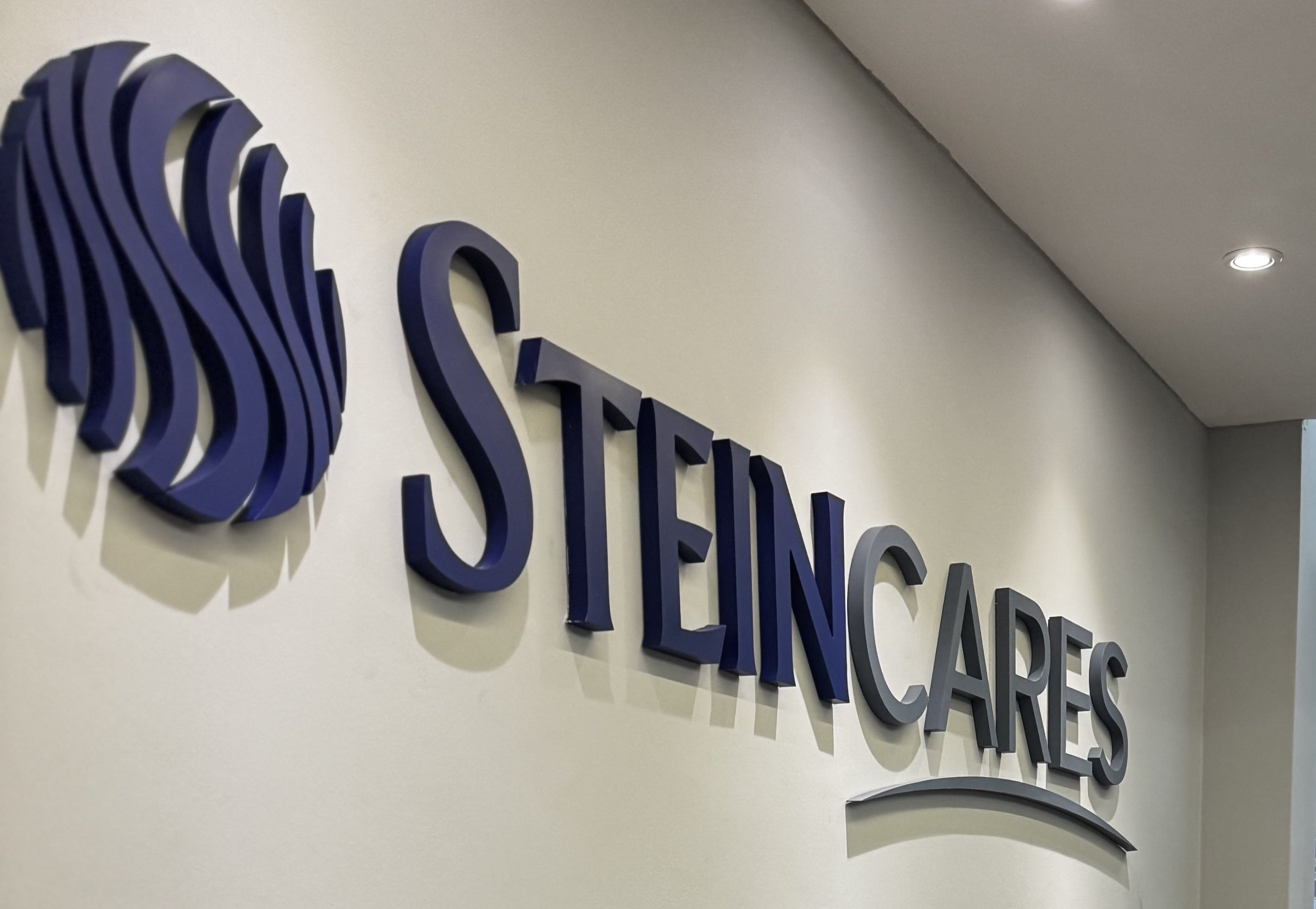 Rótulo azul y gris con logo y nombre de Stein Cares