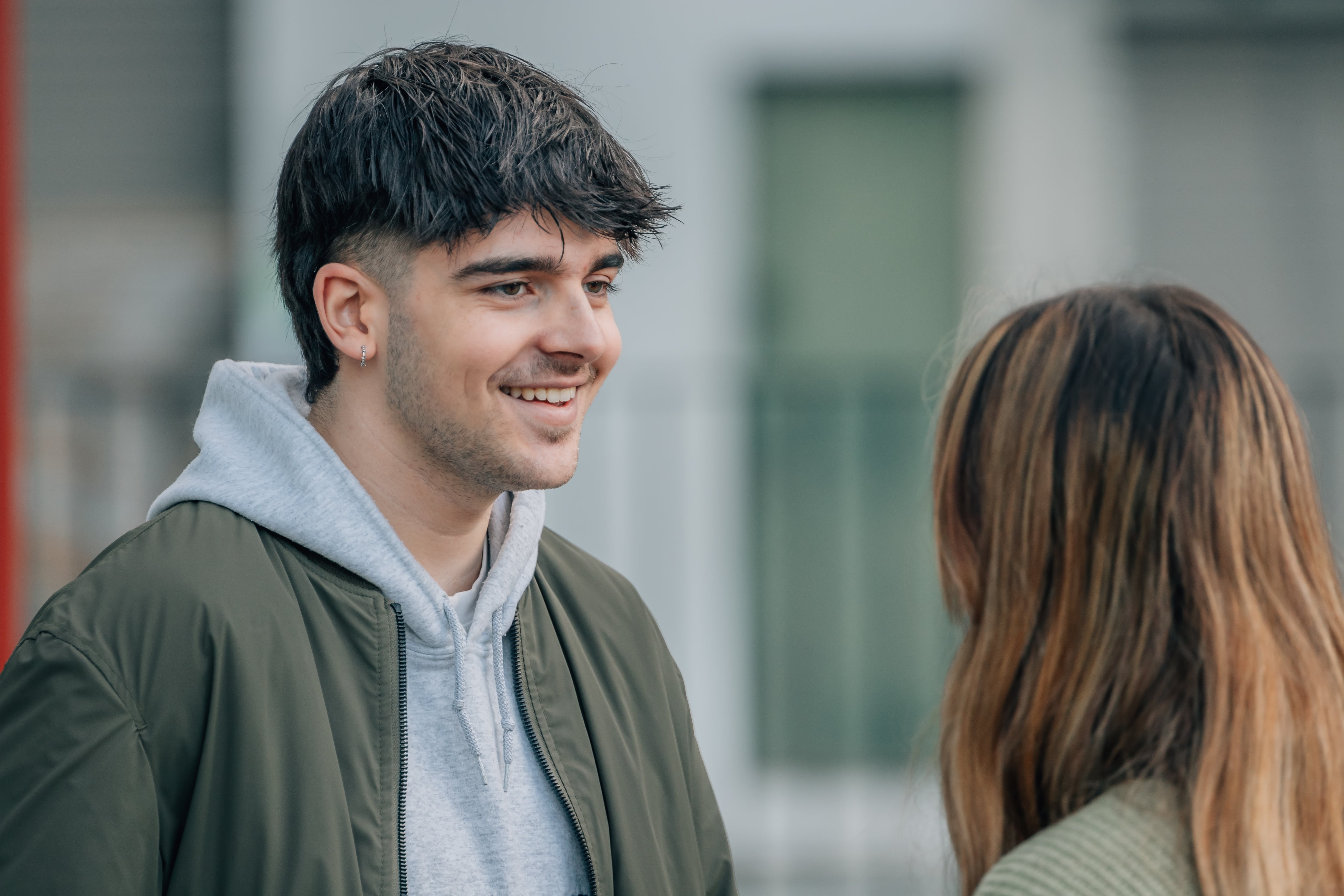 Joven pareja conversando en al calle, sonriendo, riendo. Joven habla con mujer joven, flirteo