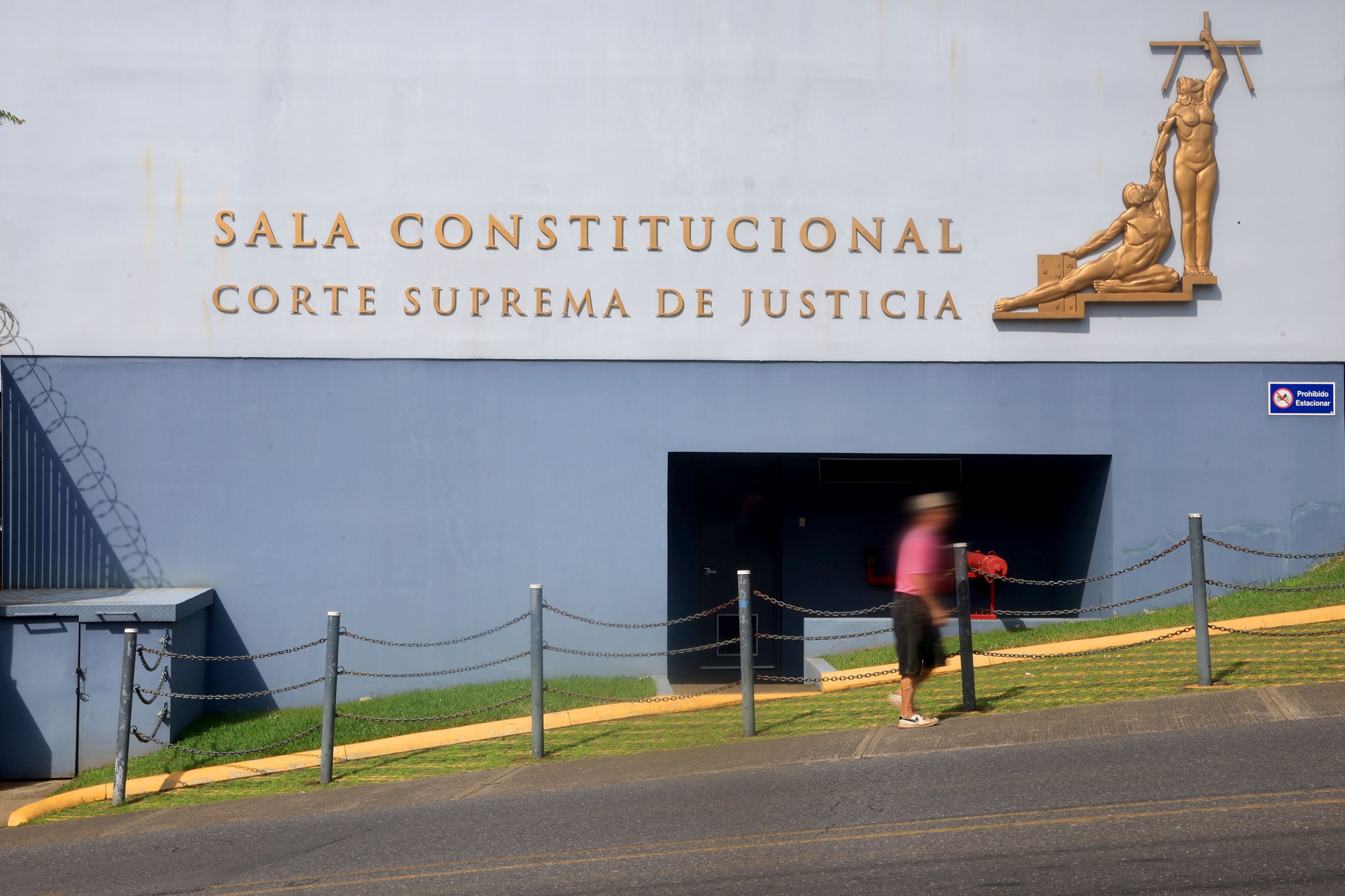 Vista frontal de la fachada de la Sala Constitucional de la Corte Suprema de Justicia de Costa Rica, con letras doradas y una escultura representativa.