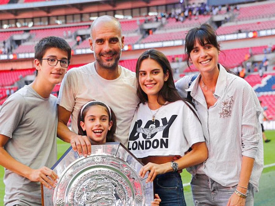 Imagen del entrenador Josep Guardiola acompañado de su esposa Cristina Serra y sus hijos en un estadio de fútbol.
