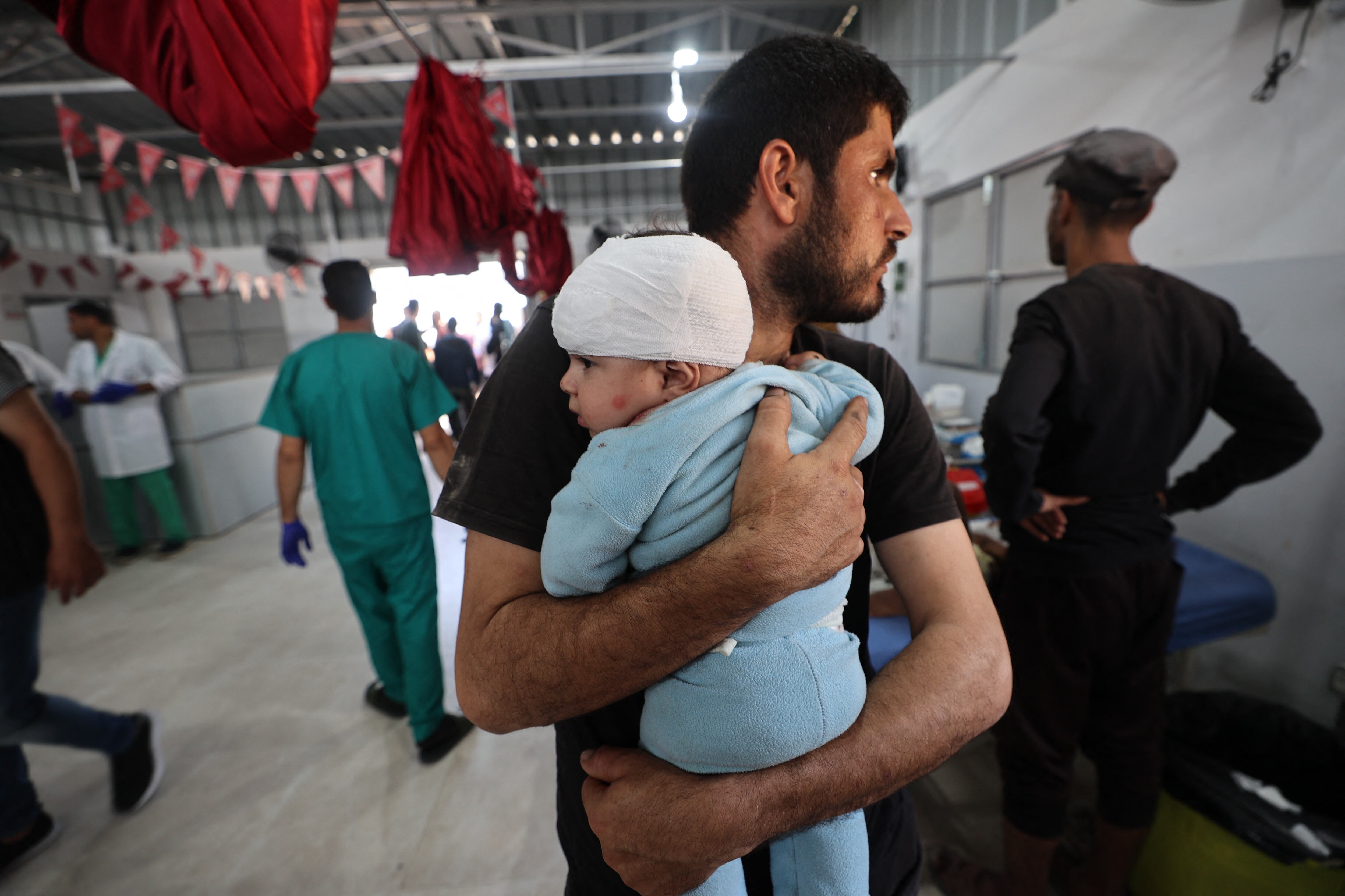 Un hombre sostiene a un niño herido tras recibir tratamiento en el Hospital Al-Awda del campo de refugiados de Nuseirat, en el centro de la Franja de Gaza, tras un ataque aéreo israelí que impactó una escuela el 19 de mayo.