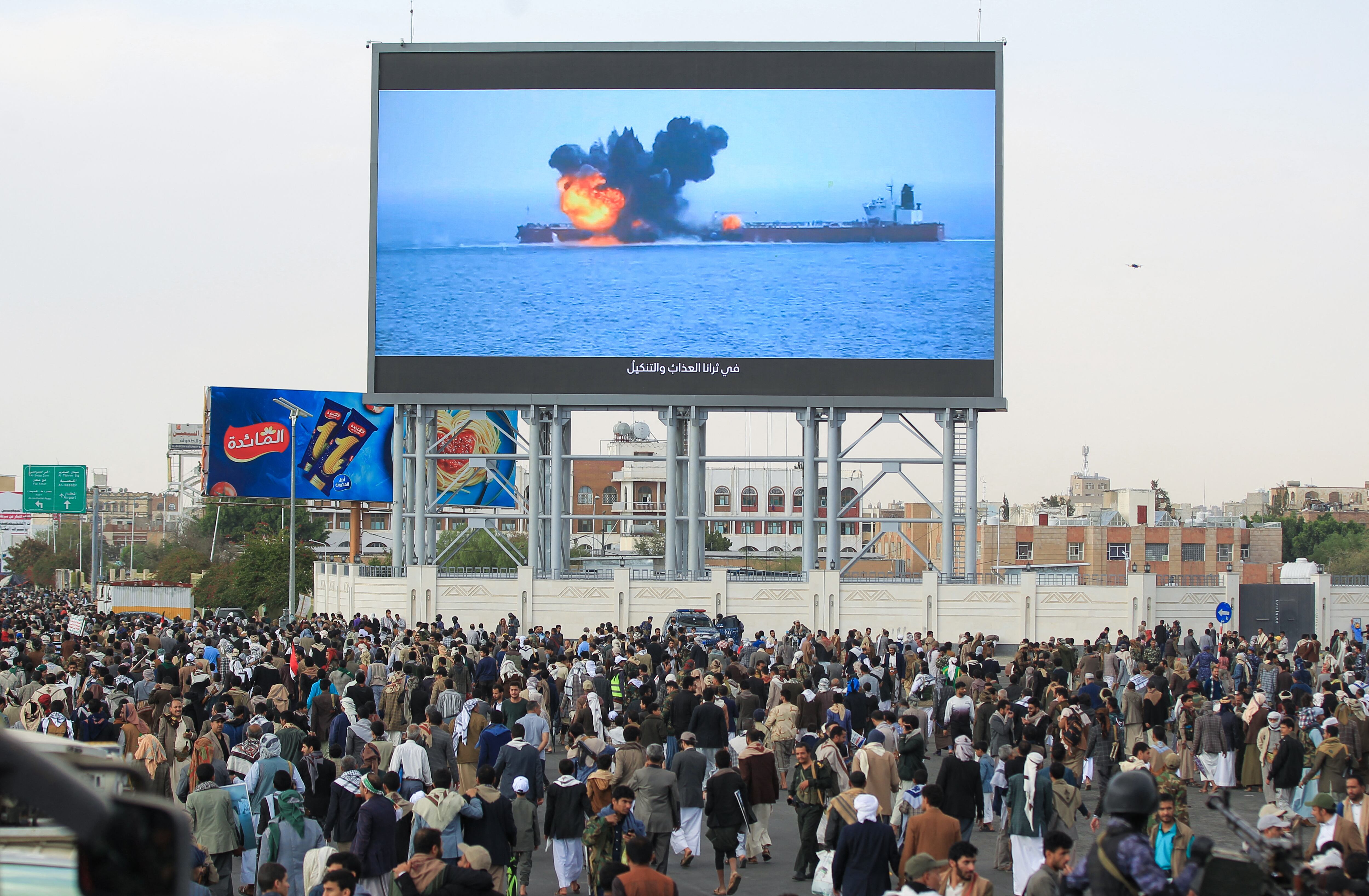 Images of a fireball exploding on a cargo ship are shown on a giant screen during a protest called for by Yemen's rebel Huthi movement in Sanaa on March 17, 2025. Huge crowds joined protests in rebel-controlled Yemen on March 17 after deadly US strikes killed dozens and sparked fears of a new cycle of violence in the conflict-torn country. (Photo by Mohamm