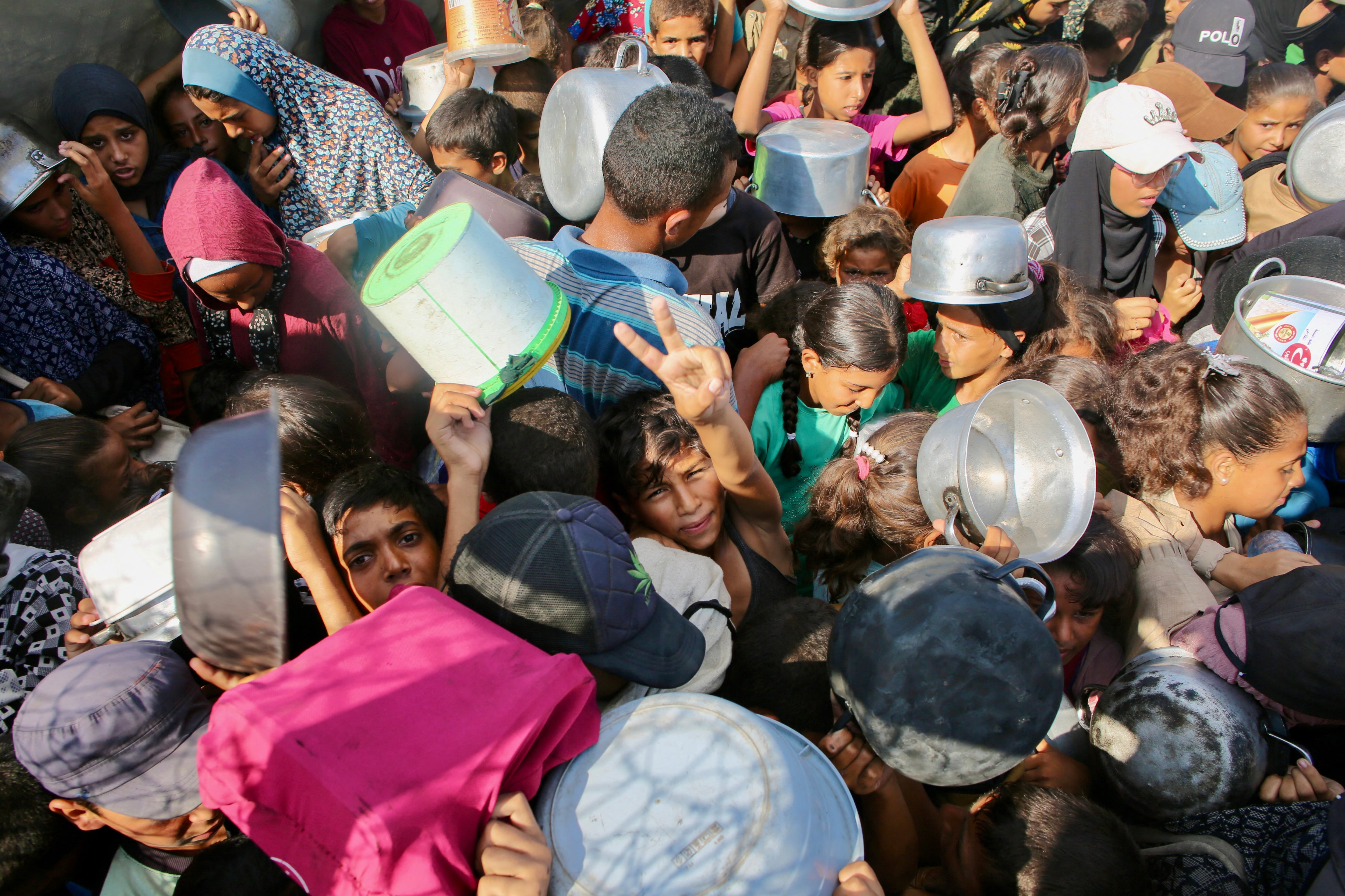Un niño palestino hizo una señal, en medio de una multitud de personas que pedían comida en un comedor social, en la zona de Mawasi, en Khan Yunis, al sur de la Franja de Gaza, este martes 22 de julio del 2025. Foto: