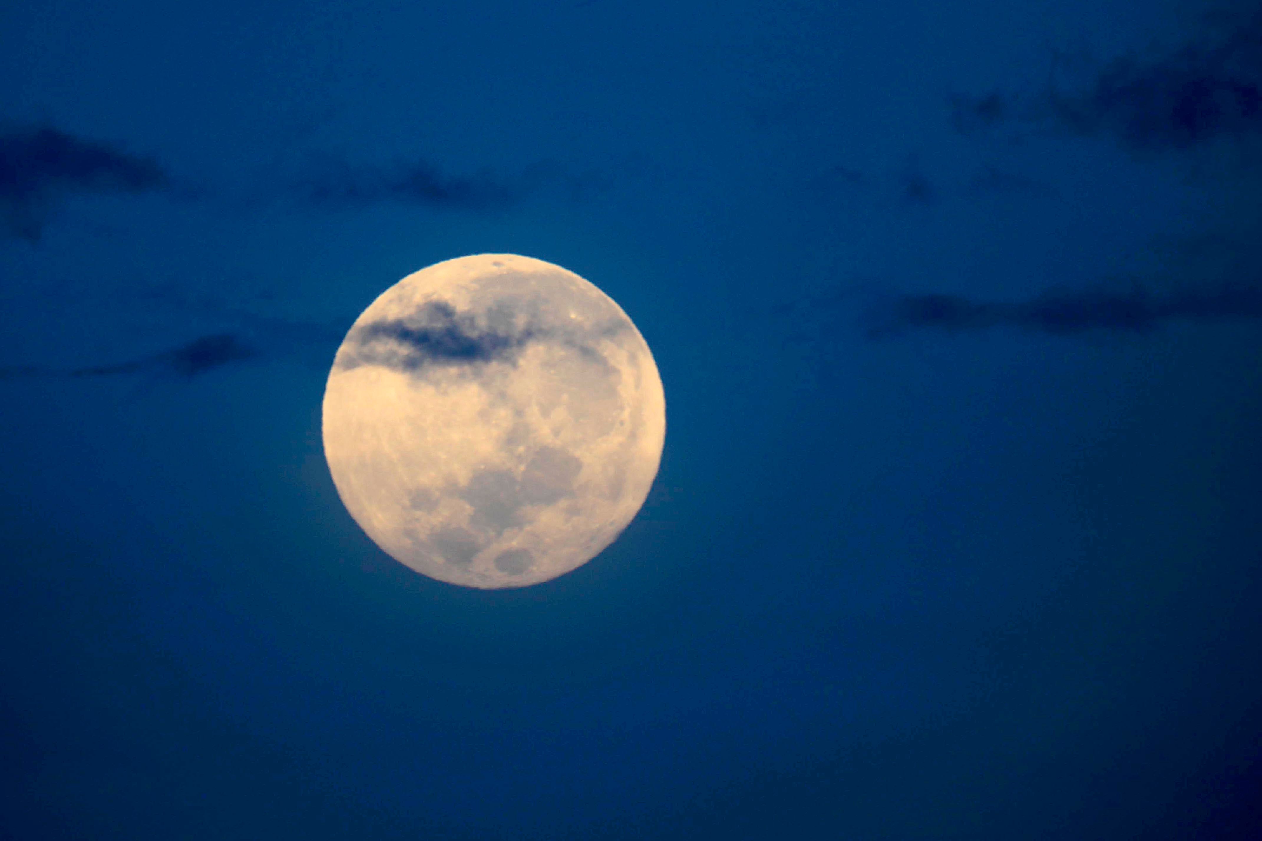 Fotografía de la Luna llena en marzo de 2025, también llamada "Luna de gusano", brillando en un cielo oscuro con algunas nubes.