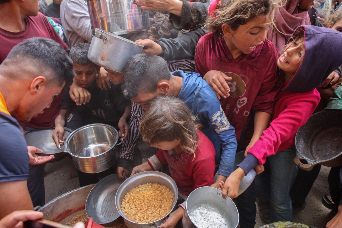 Palestinos se empujan para obtener una ración de comida caliente de una cocina benéfica instalada en el campus de la Universidad Islámica en la Ciudad de Gaza, el 12 de mayo de 2025.