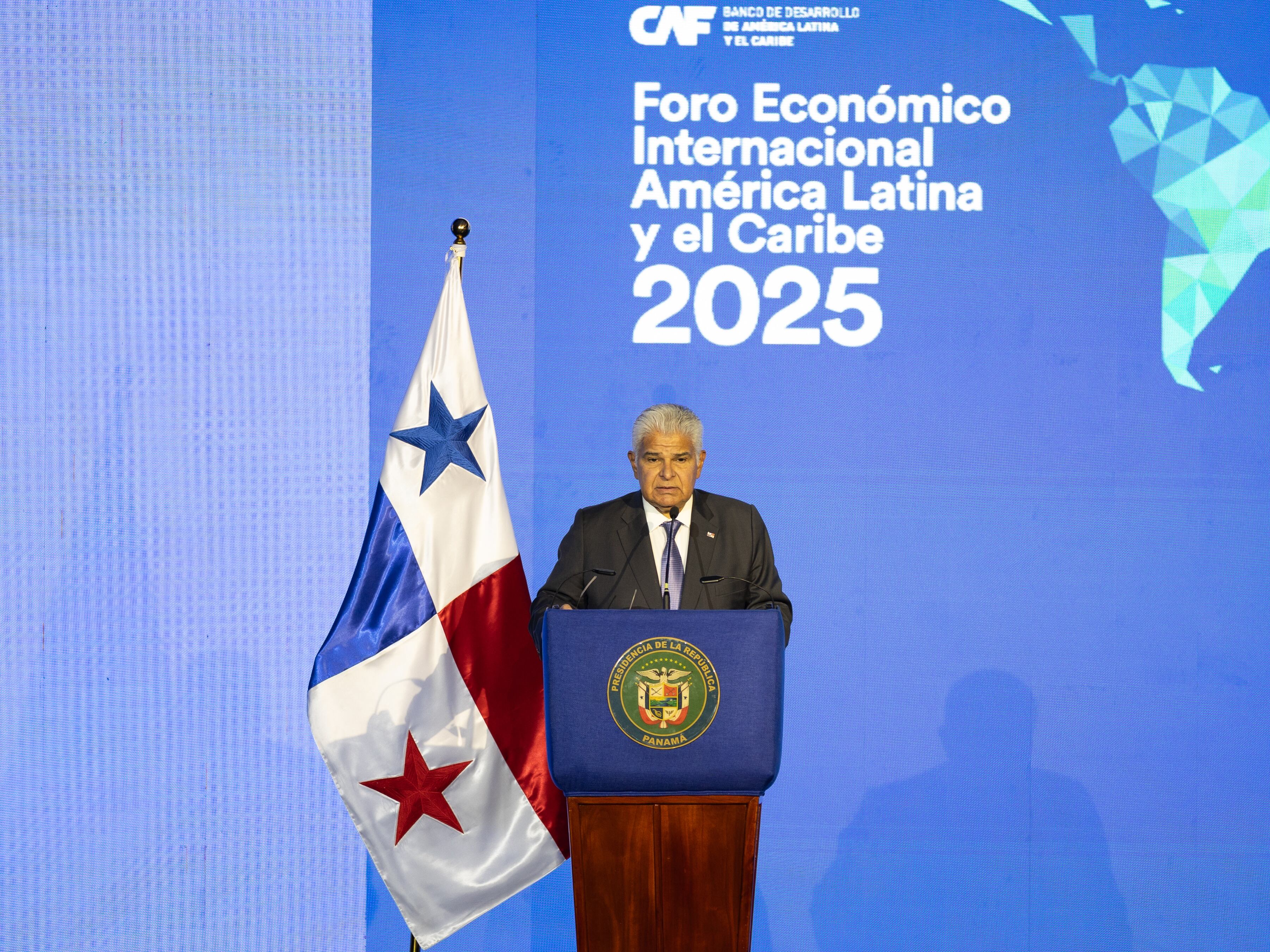 El presidente de Panamá, José Raúl Mulino, en el escenario del Foro Económico Internacional América Latina y el Caribe 2025, hablando frente a un podio con la bandera panameña al fondo.