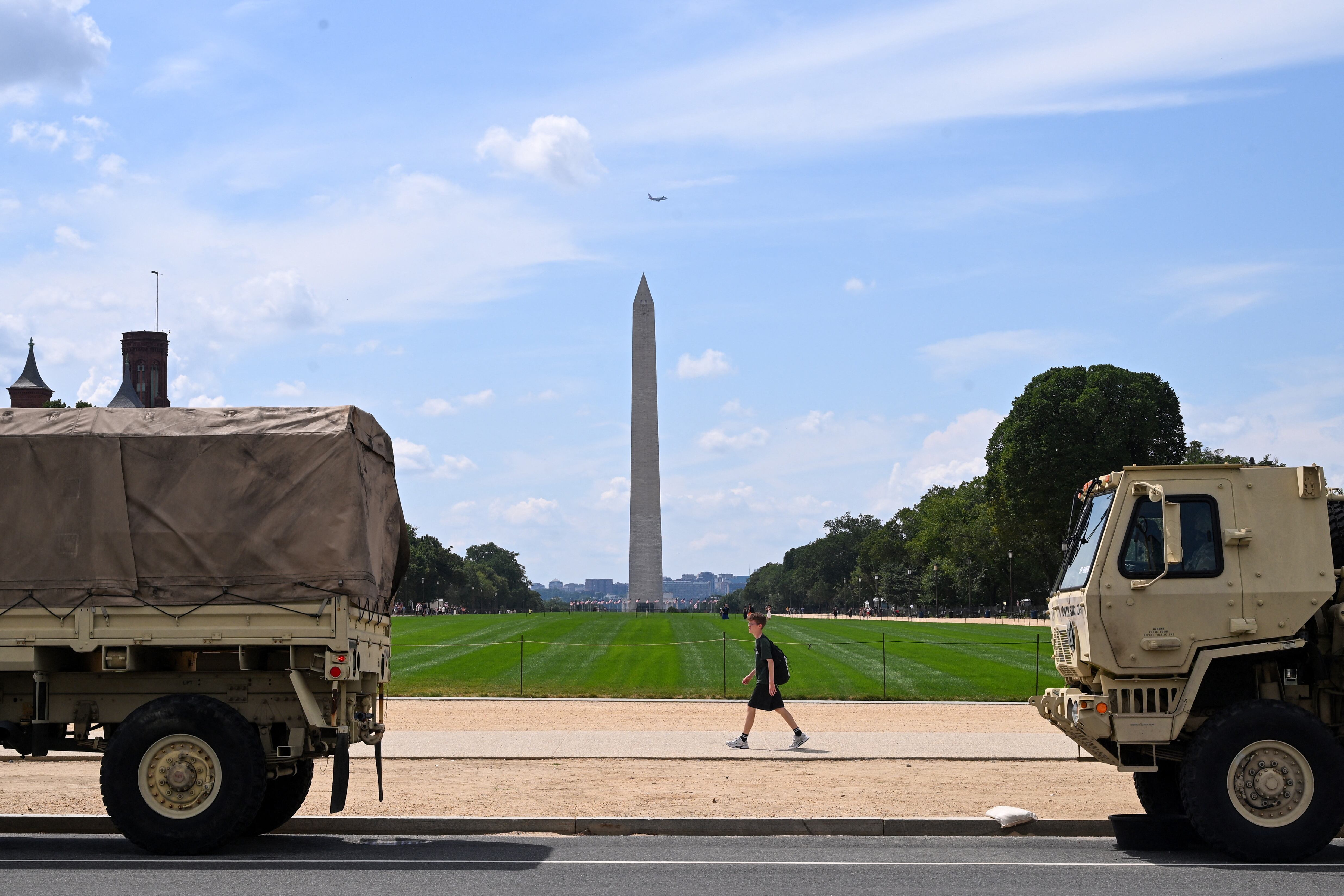 Un peatón pasa junto a vehículos militares en el National Mall de Washington, D.C., el 14 de agosto. El presidente estadounidense Donald Trump desplegó el 11 de agosto fuerzas militares y federales para frenar la delincuencia. Fotografía: