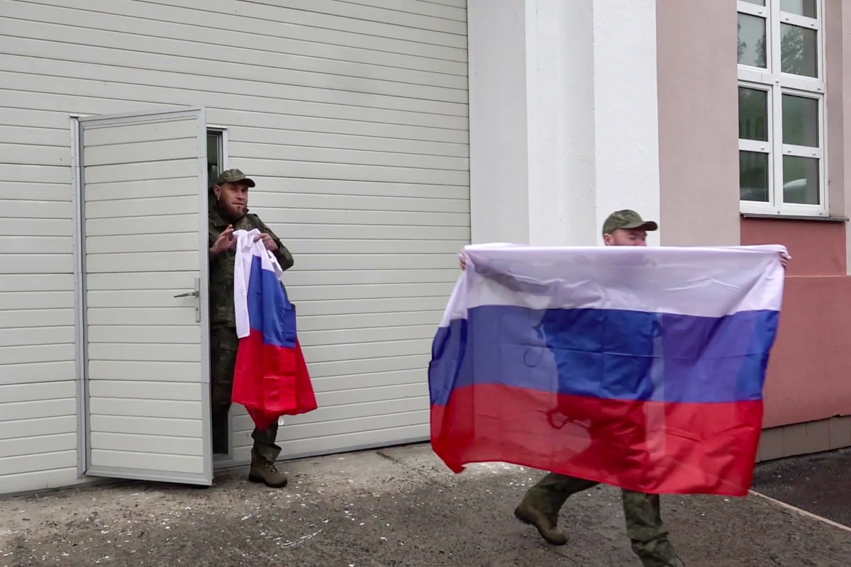 Esta captura de video difundida por el Ministerio de Defensa de Rusia el 15 de mayo de 2026 muestra a prisioneros de guerra rusos caminando con banderas para abordar un autobús tras un intercambio de prisioneros en un lugar no revelado de Bielorrusia.