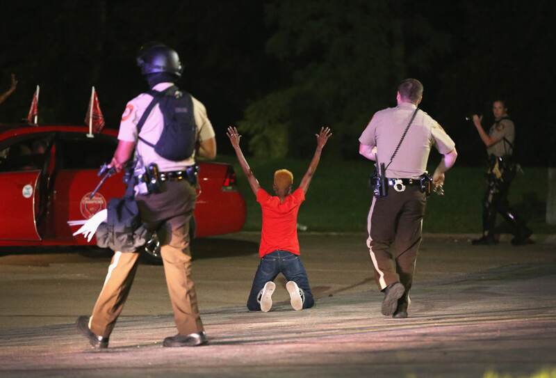La Policía rodea y detiene a dos personas en un carro el miércoles en Ferguson, Misuri, en el cuarto día de protestas tras la muerte del adolescente, Michael Brown, el sábado 9. | AFP