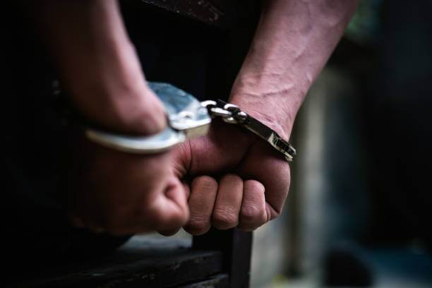 Man on the chair in Handcuffs. Rear view and Closeup ,Men criminal in handcuffs arrested for crimes. With hands in back,boy prison shackle in the jail violence concept.