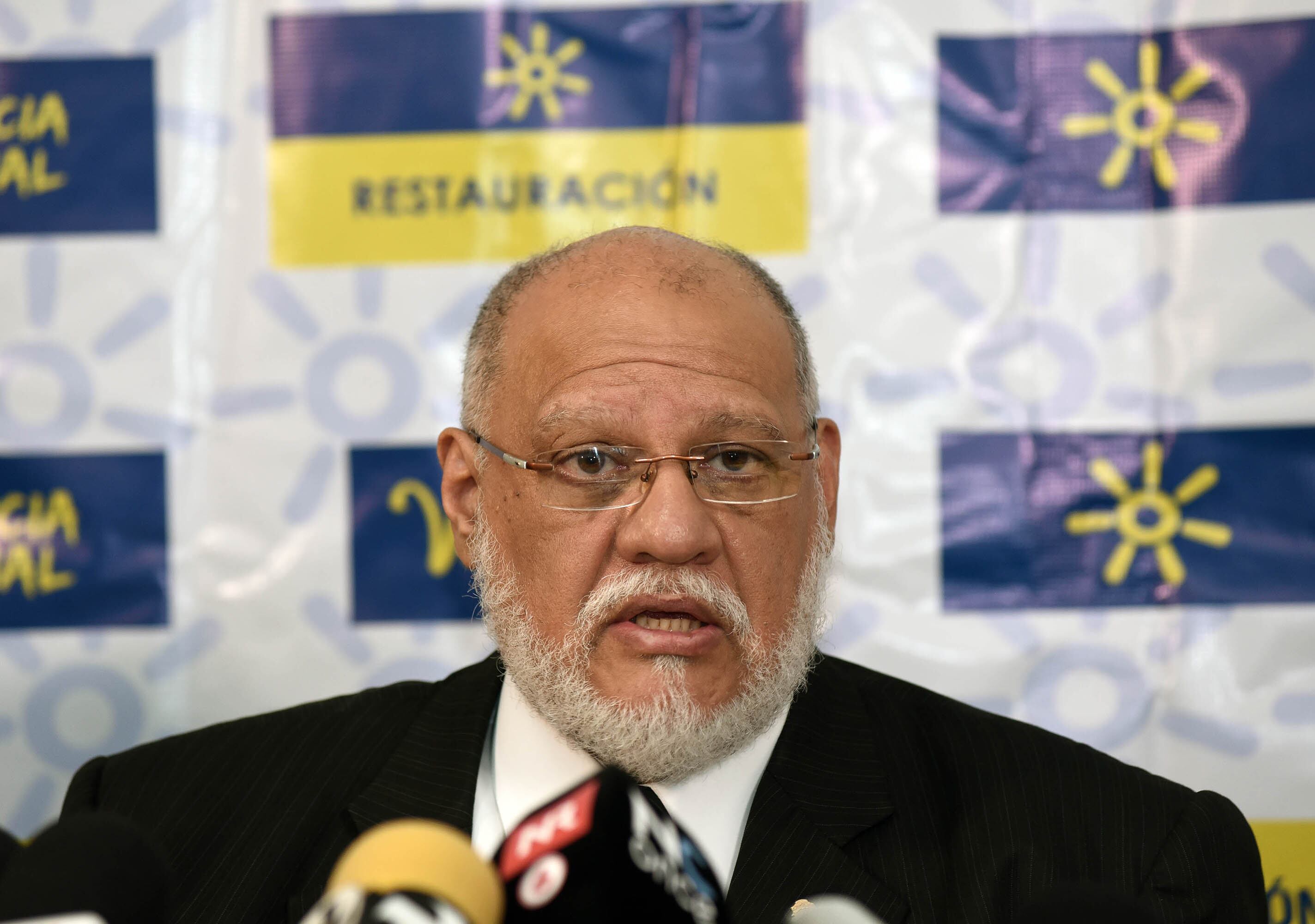 Carlos Avendaño, presidente del Partido Restauración Nacional, habla frente a un fondo con el logo de la agrupación política.
