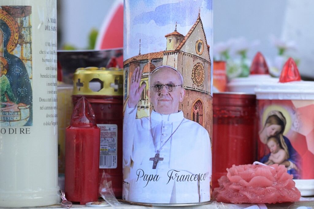 Candles are laid at the statue of John Paul II outside the Gemelli University Hospital where Pope Francis is hospitalized with pneumonia, in Rome on March 02, 2025. Pope Francis, who has been in hospital for more than two weeks with double pneumonia, is in a "stable" condition after spending a "calm night", the Vatican said on March 2, 2025. (Photo by Tiziana FABI / AFP)