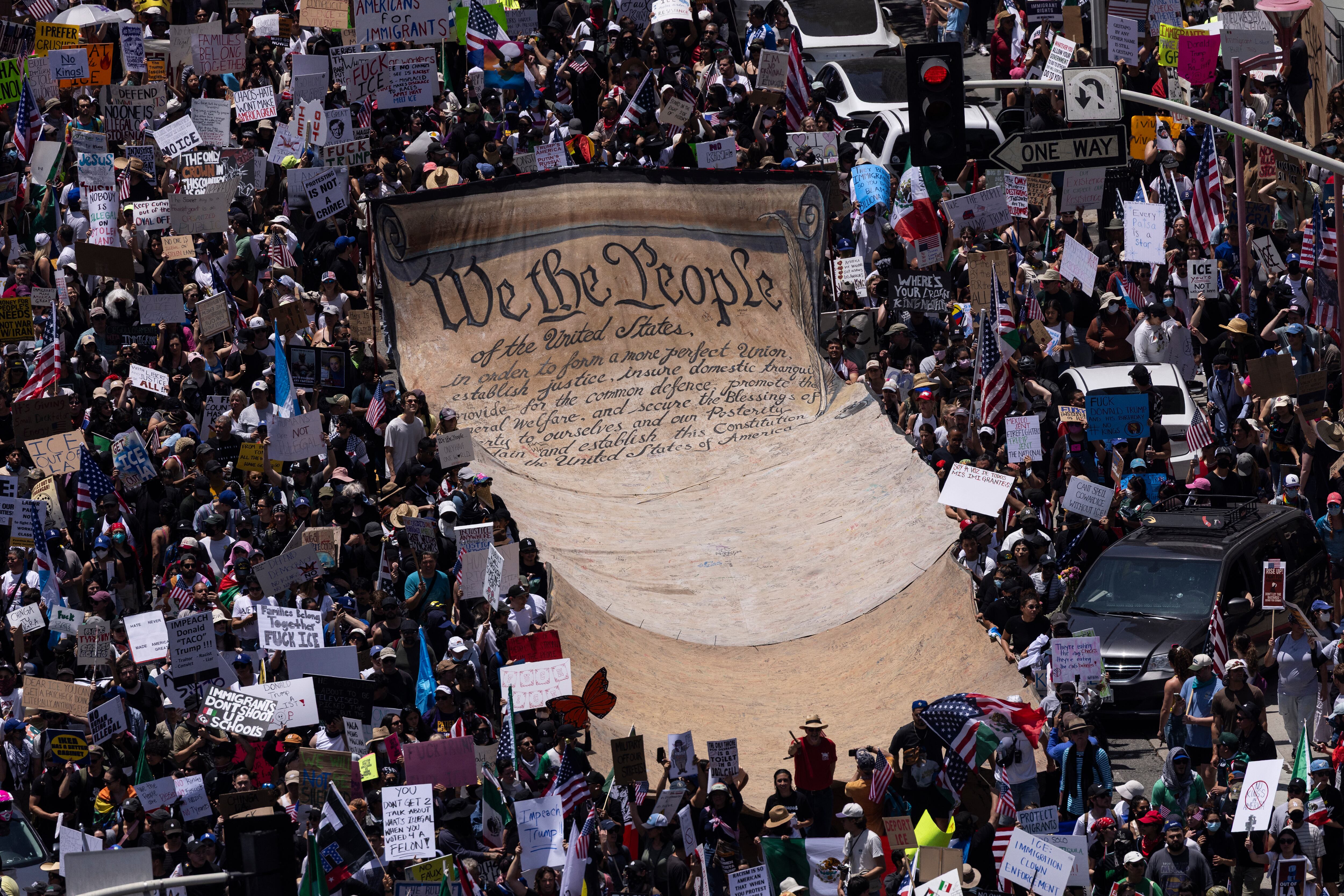 Manifestantes despliegan una pancarta gigante con la leyenda "Nosotros, el Pueblo", las tres primeras palabras del preámbulo de la Constitución de Estados Unidos, durante la manifestación "Sin Reyes" en Los Ángeles el 14 de junio de 2025, el mismo día del desfile militar del presidente Trump en Washington, D. C. En respuesta al desfile militar que celebra el 250.º aniversario del Ejército estadounidense, pero que también coincide con el 79.º cumpleaños de Trump, ha surgido un movimiento "Sin Reyes" que promete organizar protestas en más de 2.000 lugares de todo el país, incluyendo un gran desfile previsto en Los Ángeles que, según los organizadores, incluirá un globo de seis metros de altura de Trump con un pañal. (Foto de ETIENNE LAURENT / AFP)