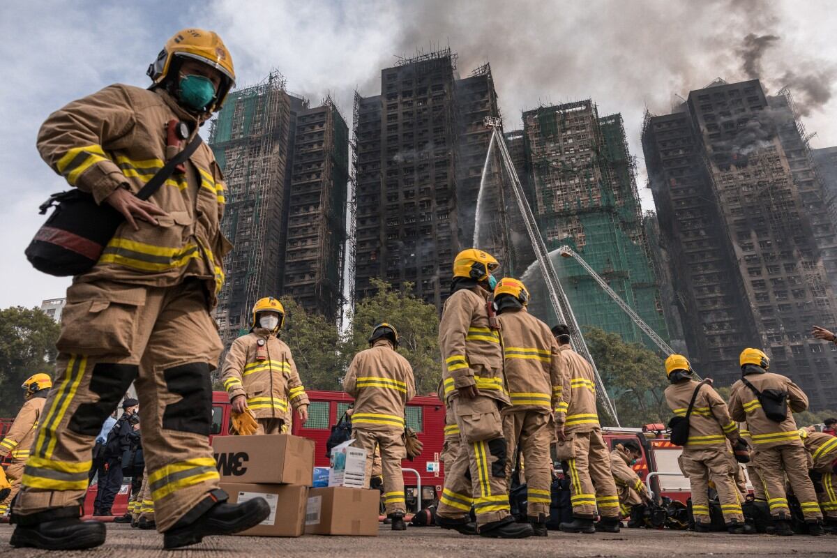 Firemen get ready after a major fire swept through several apartment blocks at the Wang Fuk Court residential estate in Hong Kong's Tai Po district on November 27, 2025. Hong Kong firefighters were scouring a still-burning apartment complex for hundreds of missing people on November 27, a day after the blaze tore through the high-rises, killing at least 44. (Photo by Dale DE LA REY / AFP)