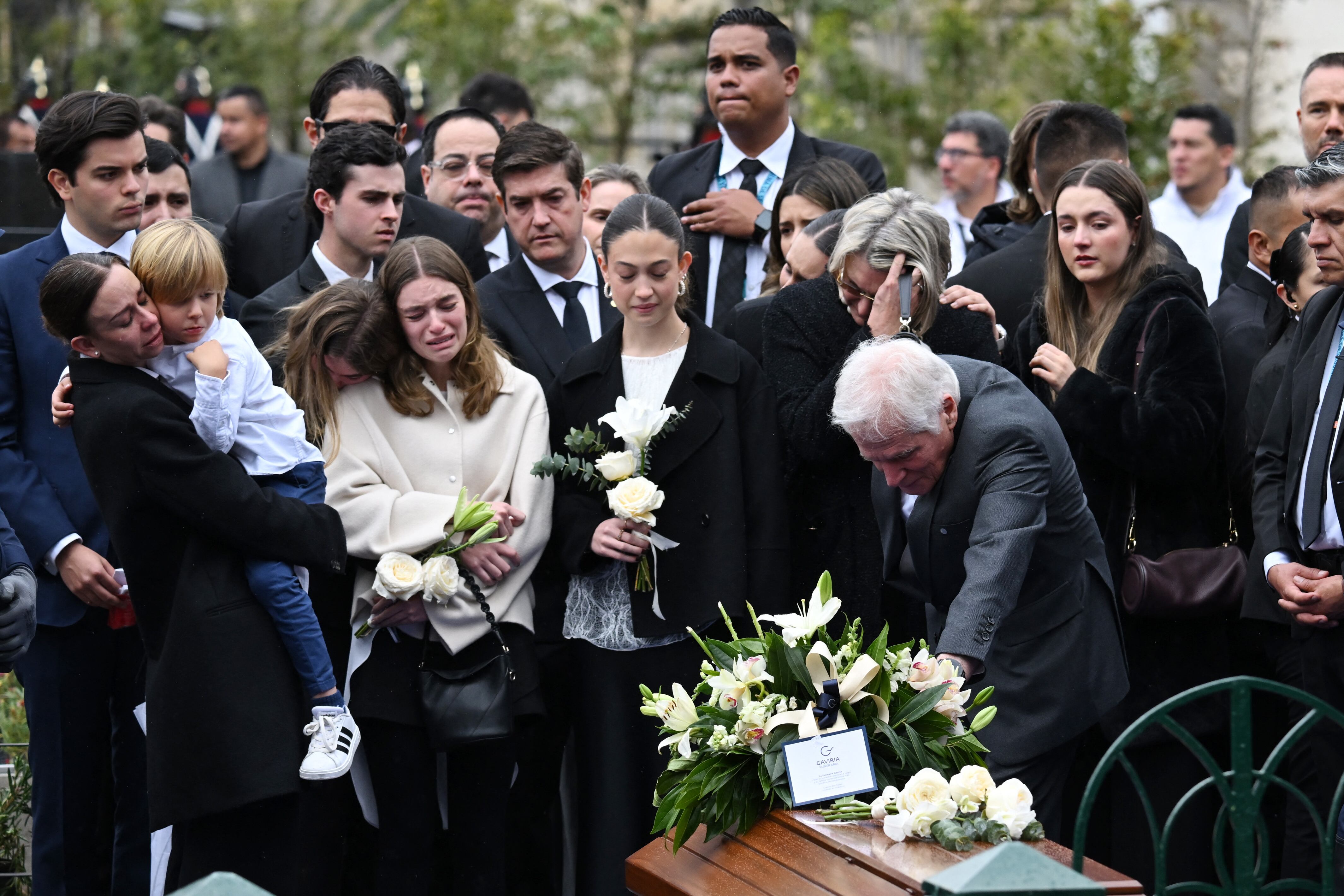 Miguel Uribe Londono (R), father of slain Colombian presidential candidate Miguel Uribe, touches the coffin of his son as his daughter-in-law, widow Mar�a Claudia Tarazona (L), among other relatives, mourns during the burial at the Central Cemetery in Bogota on August 13, 2025. Colombian presidential candidate Miguel Uribe died two months after being shot in the head at a campaign event, his wife announced early August 11, 2025, as the attack rekindled fears of a return to the nation's violent past. (Photo by RAUL ARBOLEDA / AFP)