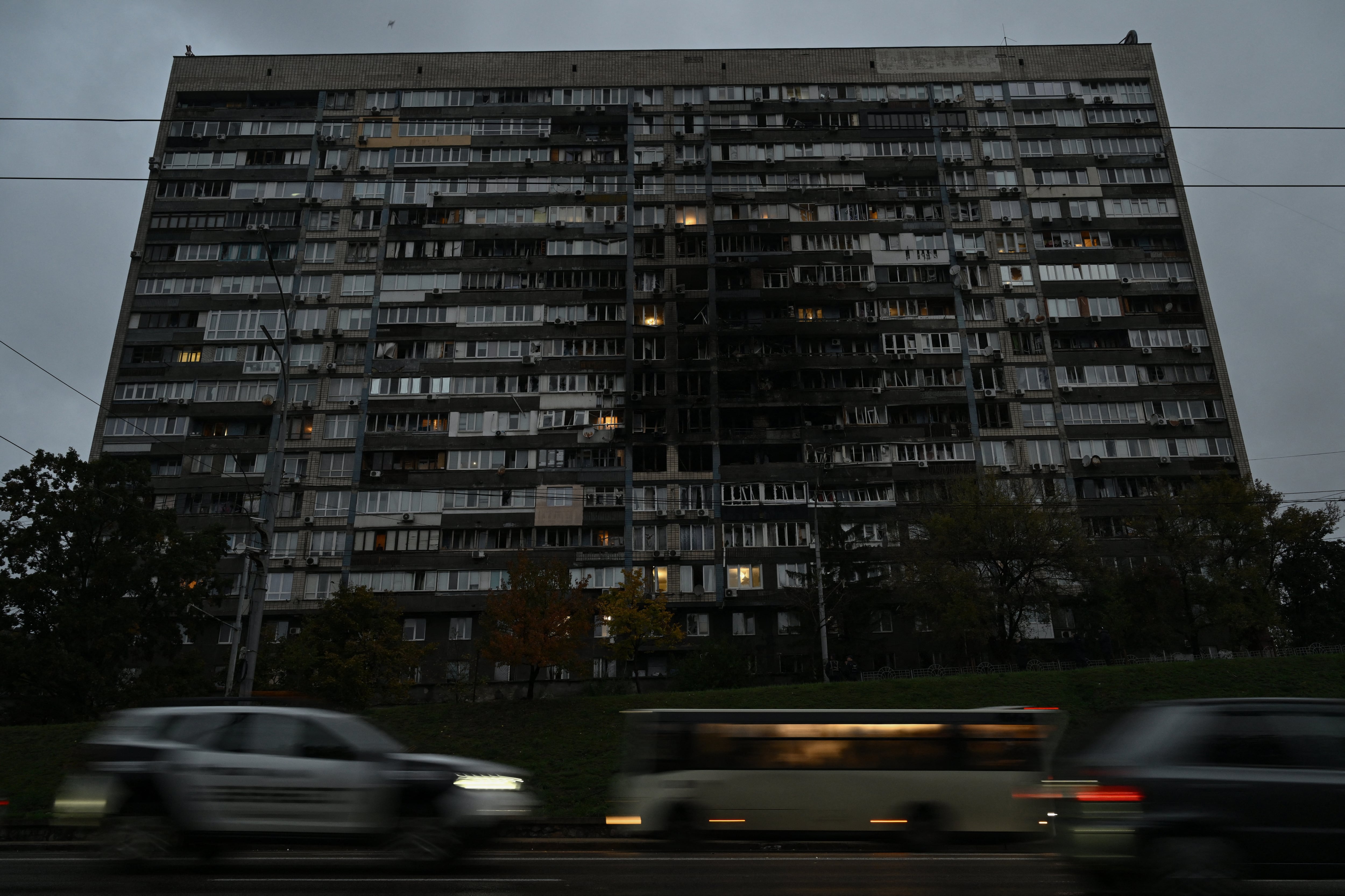 Vehículos pasan junto a un edificio residencial dañado durante los masivos ataques con drones y misiles rusos contra la capital ucraniana, Kiev, el 10 de octubre, durante la invasión rusa de Ucrania. Fotografía: