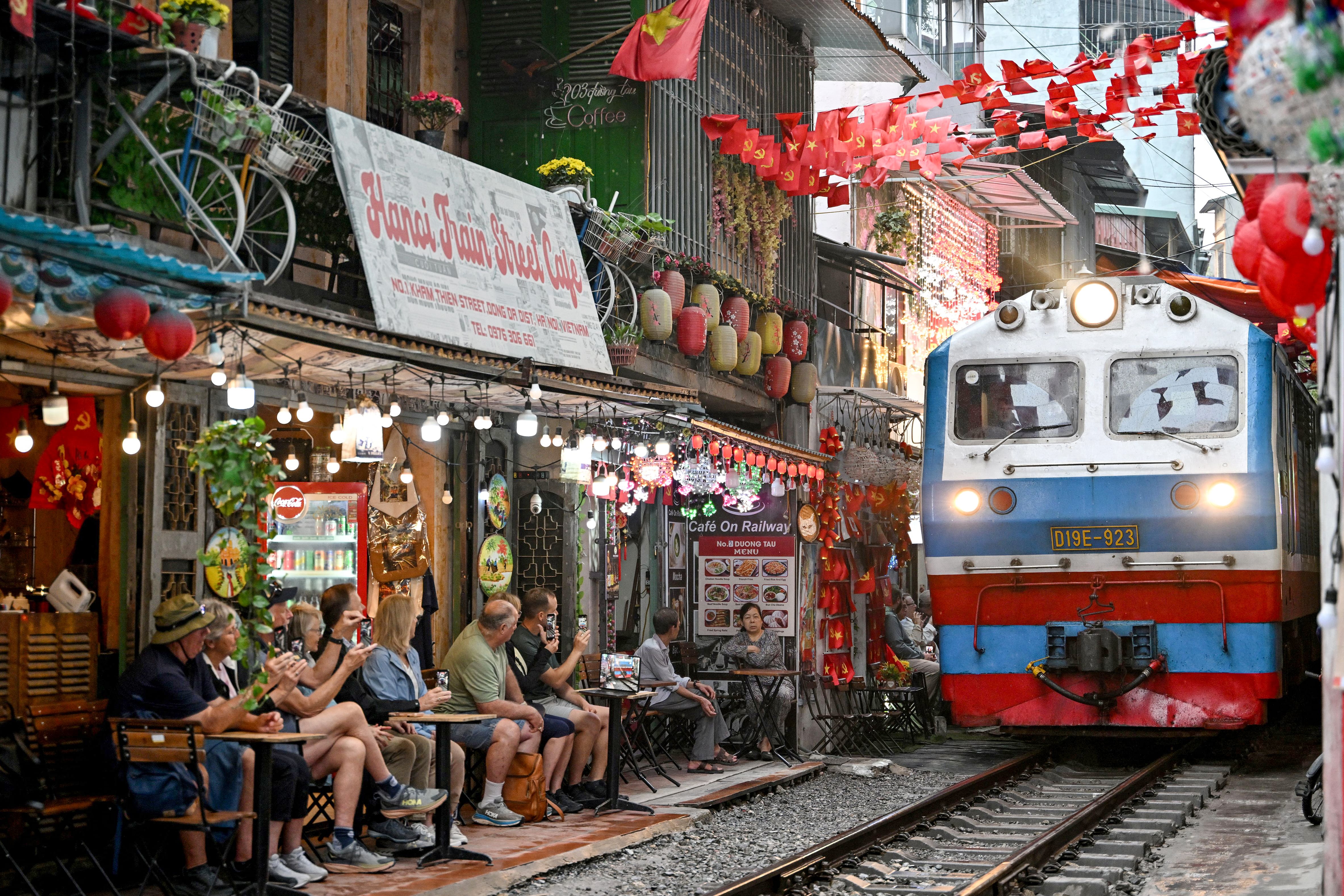 Turistas toman fotografías mientras un tren pasa por la vía férrea de la popular Calle del Tren, en Hanói, el 25 de febrero de 2026. (Foto de Nhac Nguyen / AFP)