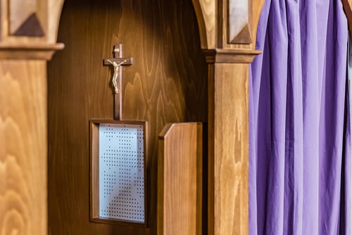 Confesionario con un cristo en la pared, símbolo del sacramento de la confesión en la Iglesia católica.