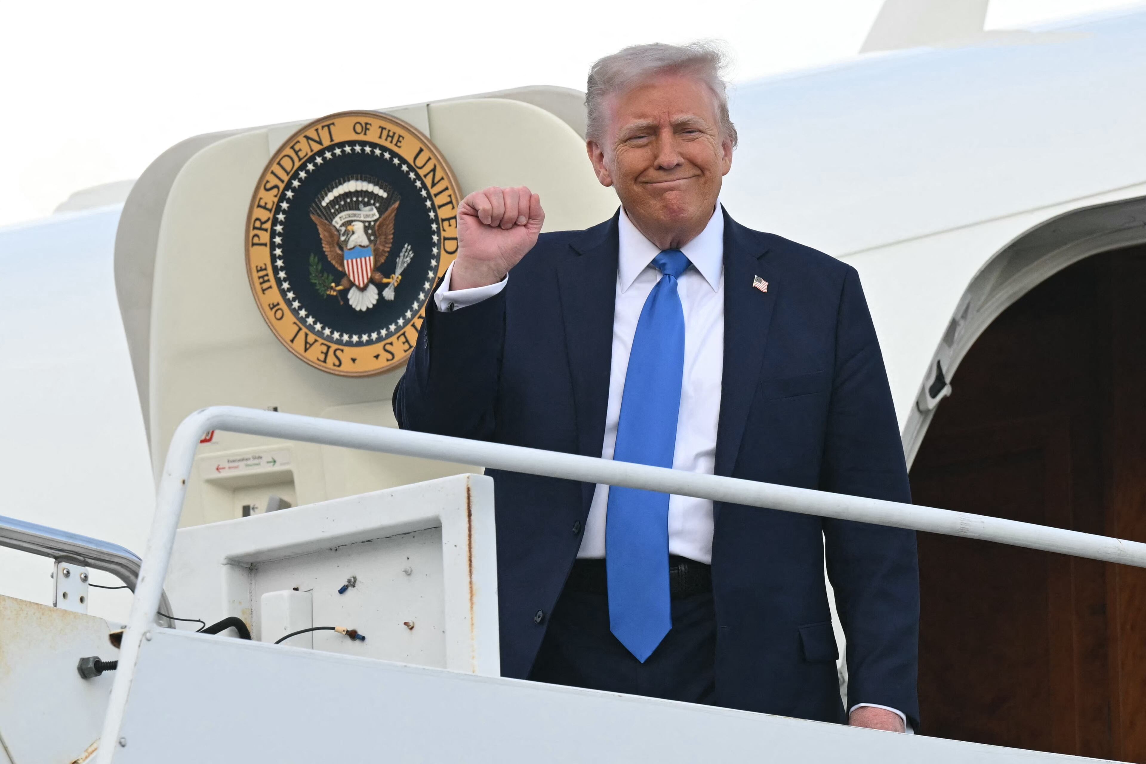 El presidente de Estados Unidos, Donald Trump, levanta el puño al descender del Air Force One a su llegada al Aeropuerto Nacional de Tuscaloosa en Tuscaloosa, Alabama, el 1 de mayo de 2025. Trump se dirige a la Universidad de Alabama para pronunciar un discurso en la ceremonia de graduación.