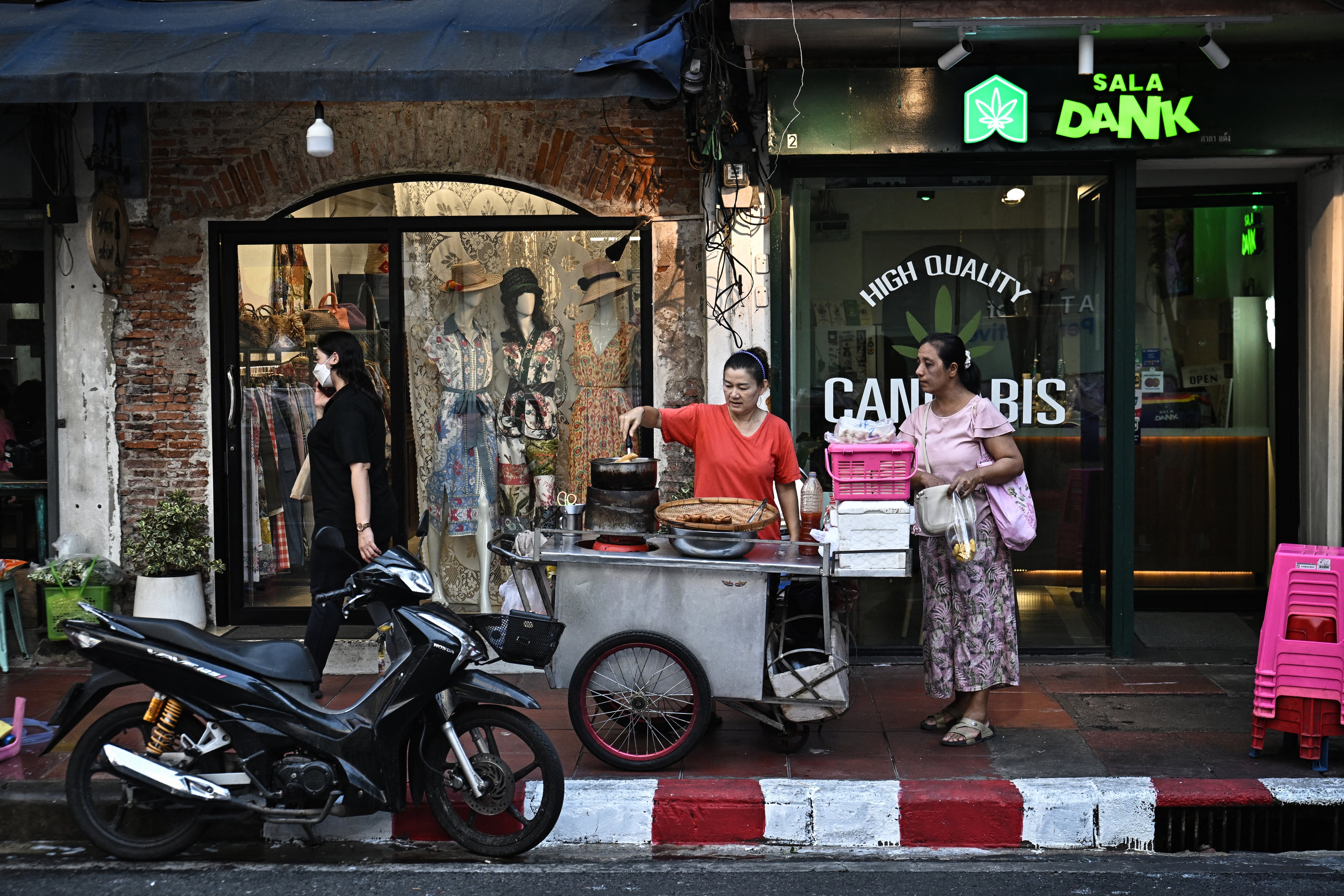 Esta foto, tomada el 30 de abril de 2026, muestra a un vendedor ambulante preparando comida para un cliente a lo largo de la calle Silom en Bangkok.