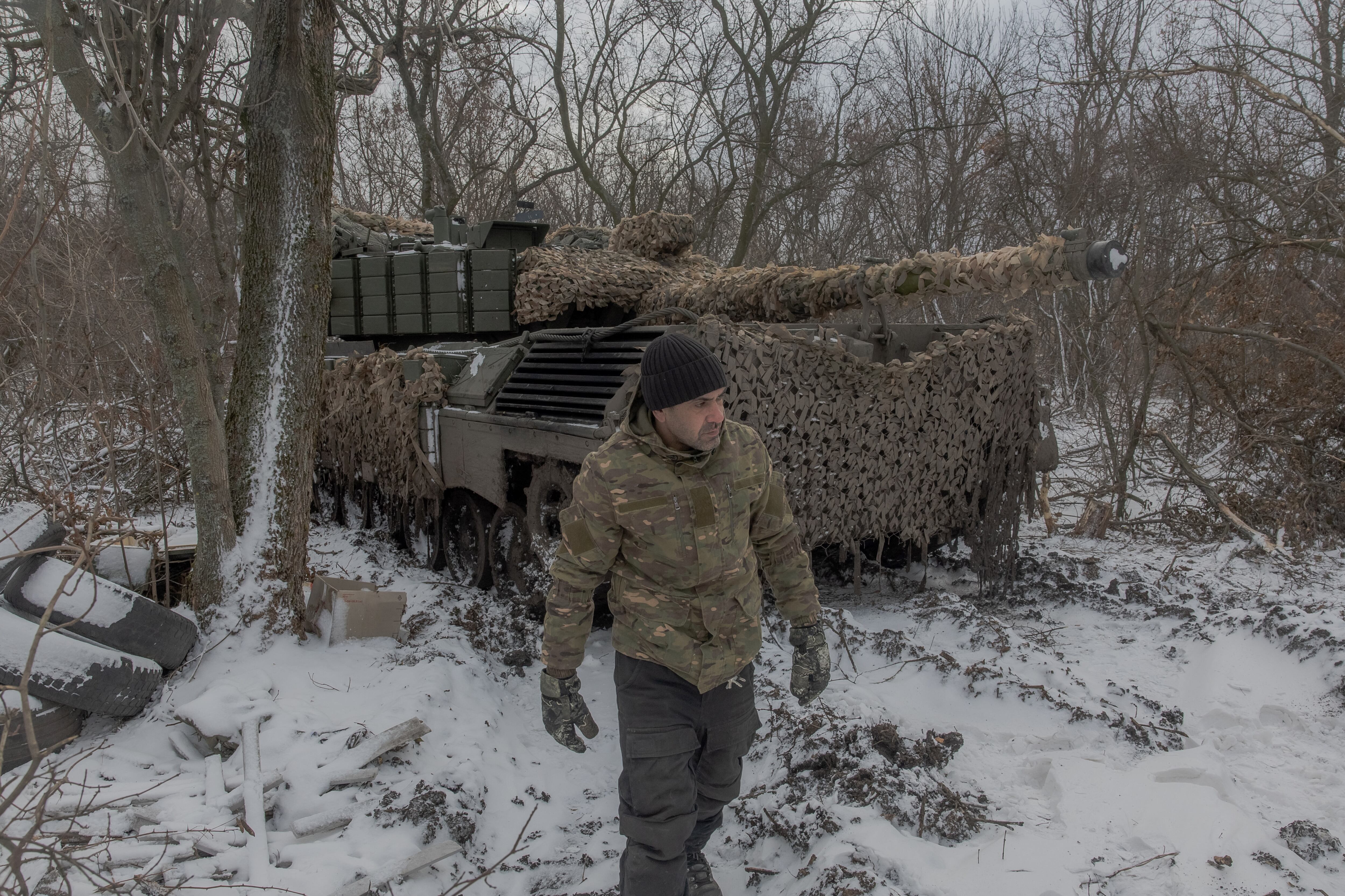 Soldado ucraniano camina frente a un tanque camuflado en un bosque nevado en la región de Kursk durante el conflicto entre Rusia y Ucrania.