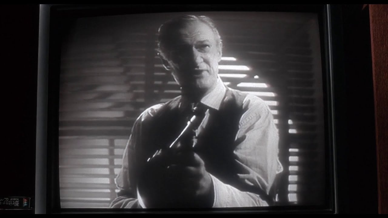 Un hombre en una escena en blanco y negro sosteniendo una pistola, tomada de Angels with Filthy Souls, película ficticia dentro de Mi Pobre Angelito.