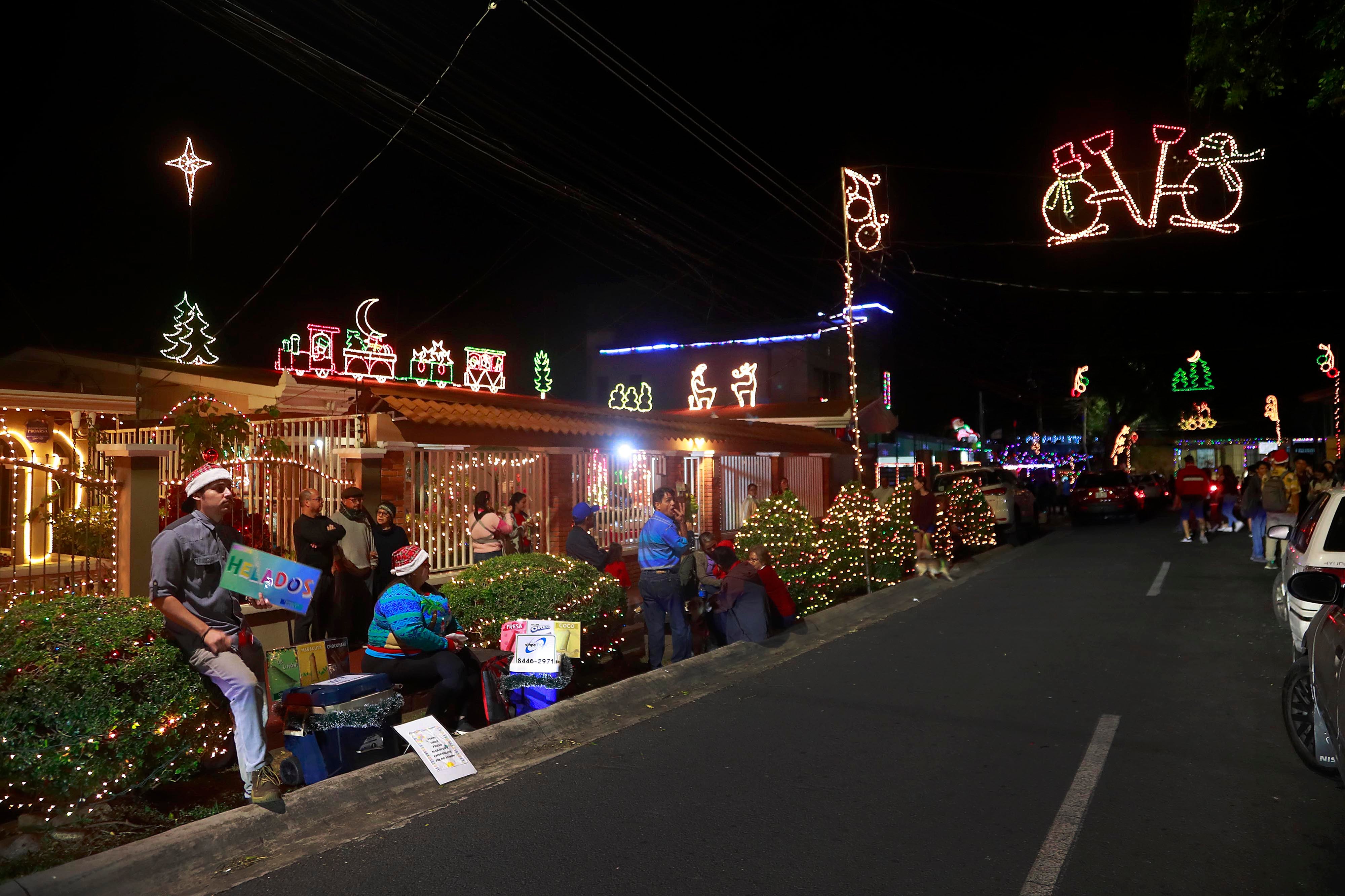 07/12/2023 San Joaquín de Flores. Vecinos de barrio La Cruz reviven la tradición de todos los años con la iluminación del frente de sus casas y árboles de las aceras, además de la venta de comidas que acerca a decenas de personas, quienes todas las noches se acercan para compartir en la calle misma y disfrutar de un verdadero ambiente navideño.