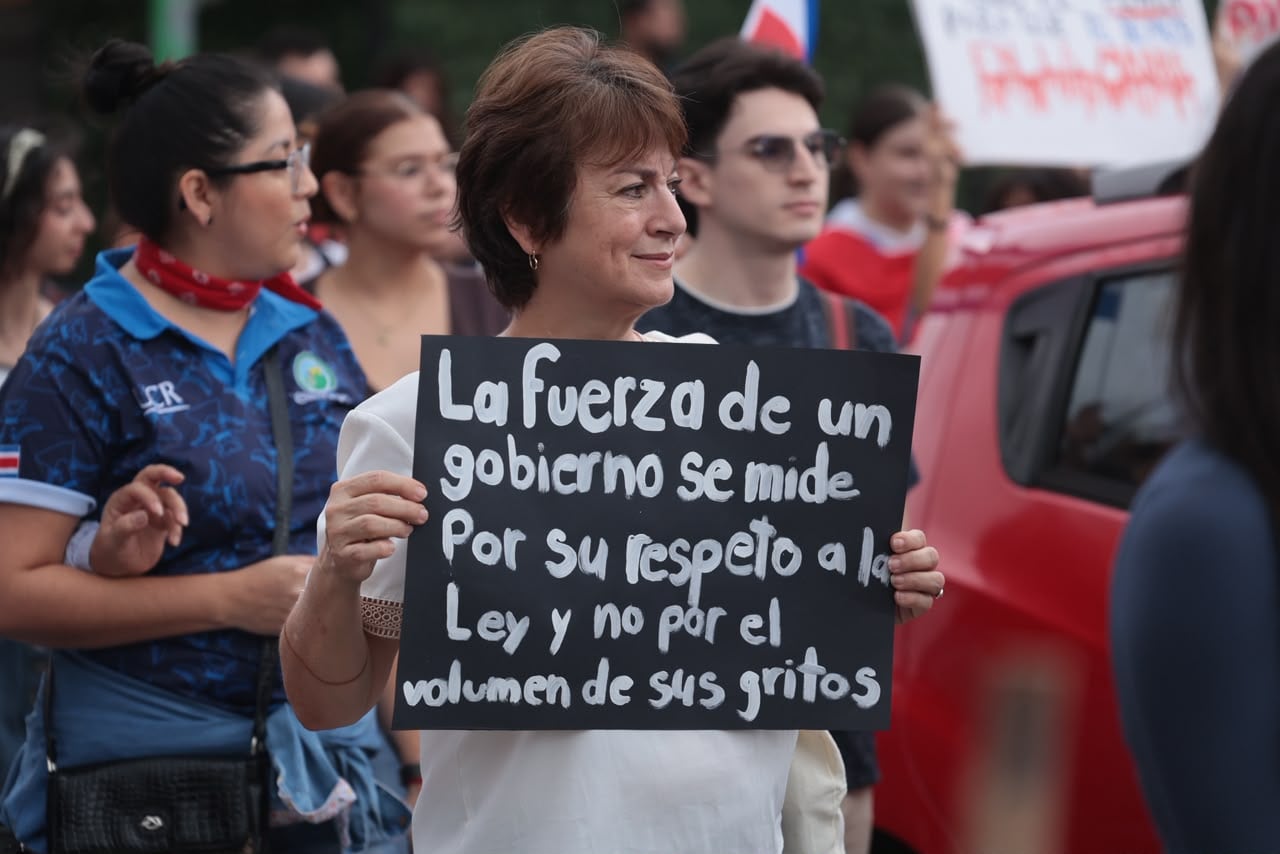 Cientos de personas con carteles y banderas se dirigen al Plantón por la Justicia Democrática en la plaza de la Democracia en San José.