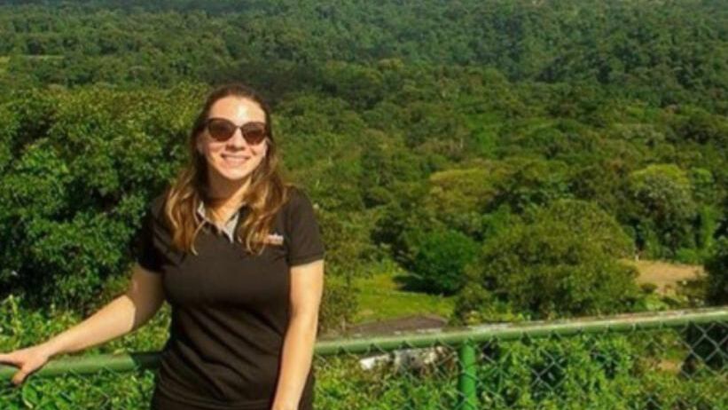 Mujer joven con gafas de sol sonríe frente a un paisaje montañoso, sobreviviente de accidente aéreo en Escazú.