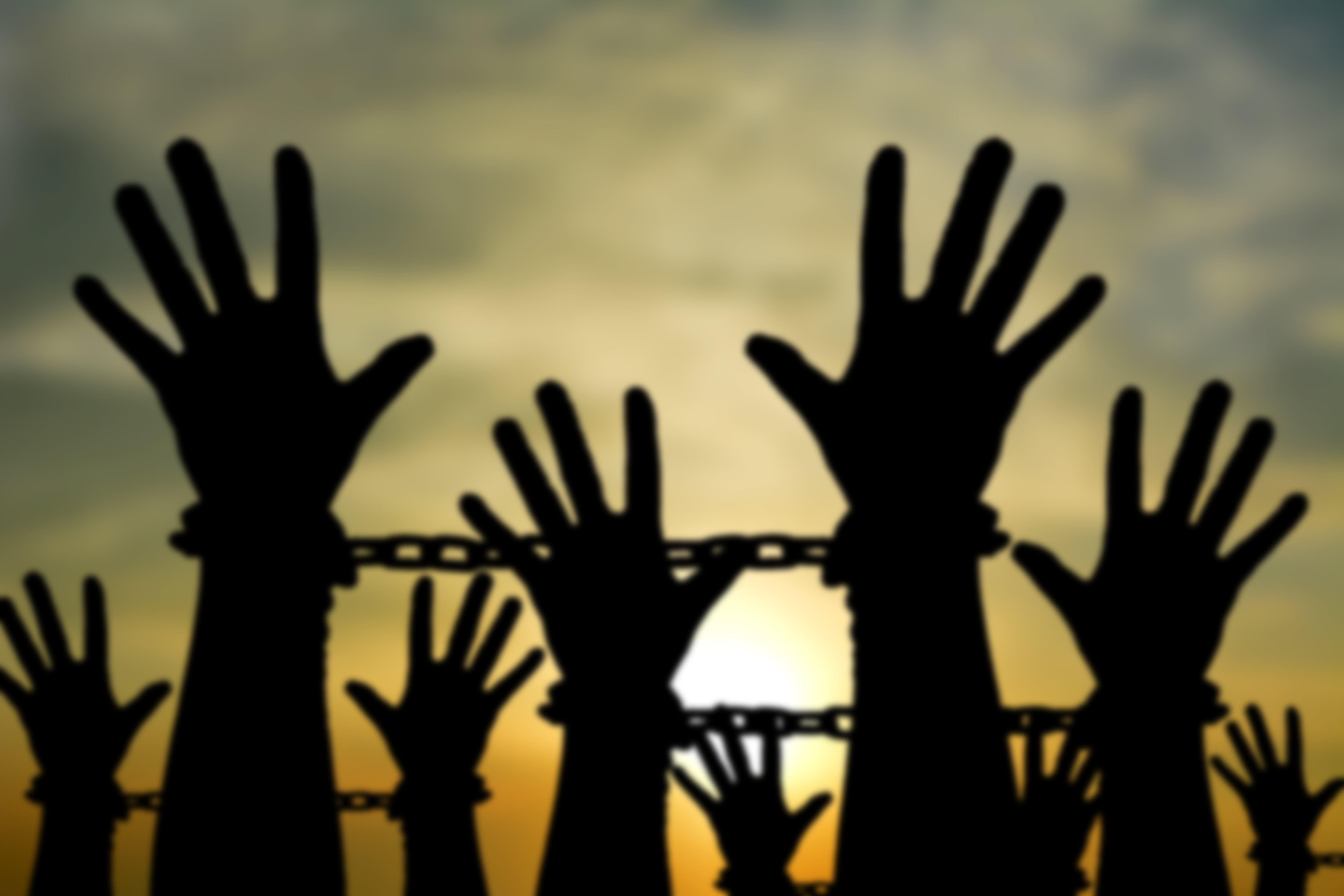 Manos alzadas y encadenadas con el atardecer de fondo