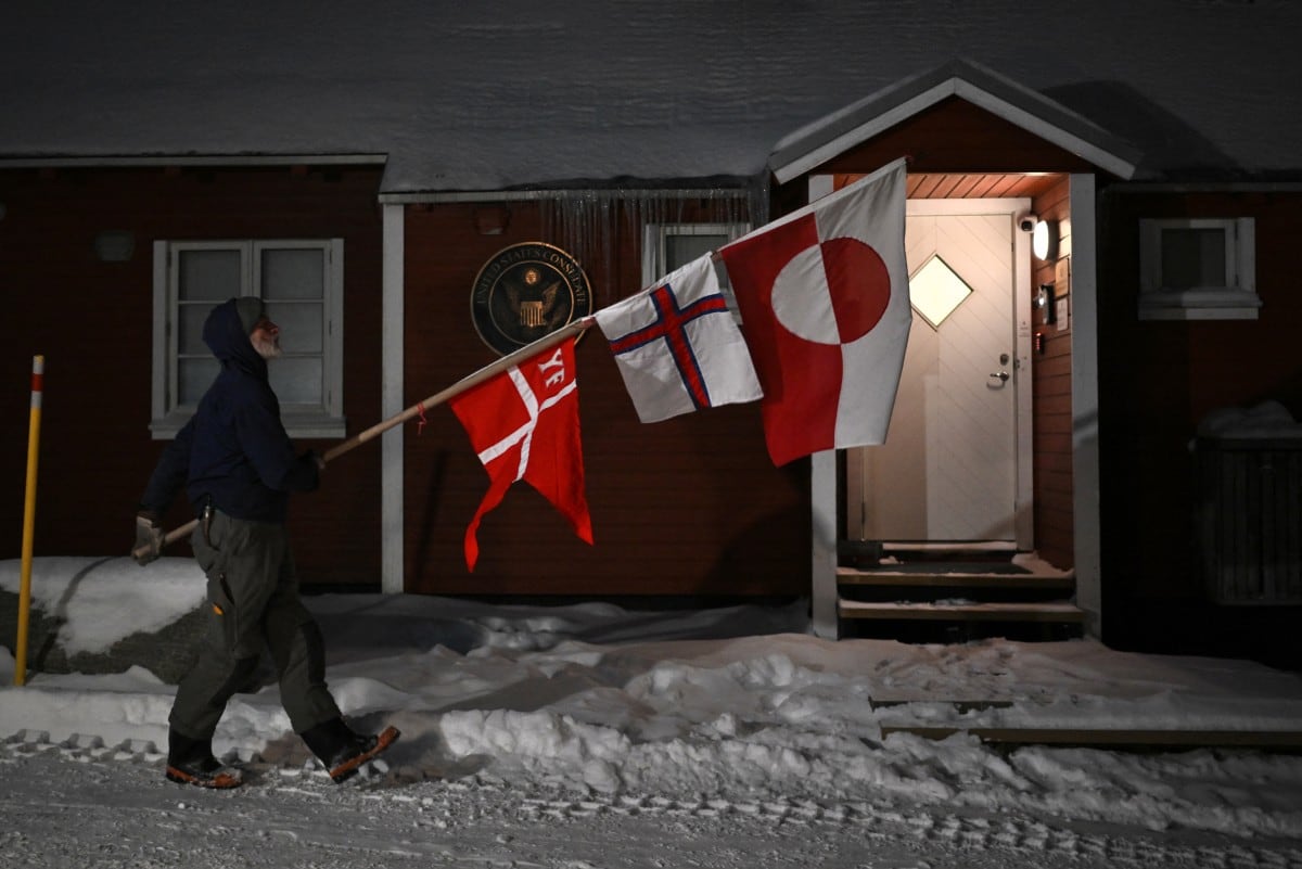 Jens Kjeldsen, carpintero y exjuez de Groenlandia, camina de un lado a otro con banderas de Dinamarca, las Islas Feroe y Groenlandia (Reino de Dinamarca) mientras protesta frente a la cabaña de madera del consulado de Estados Unidos en Nuuk, Groenlandia.