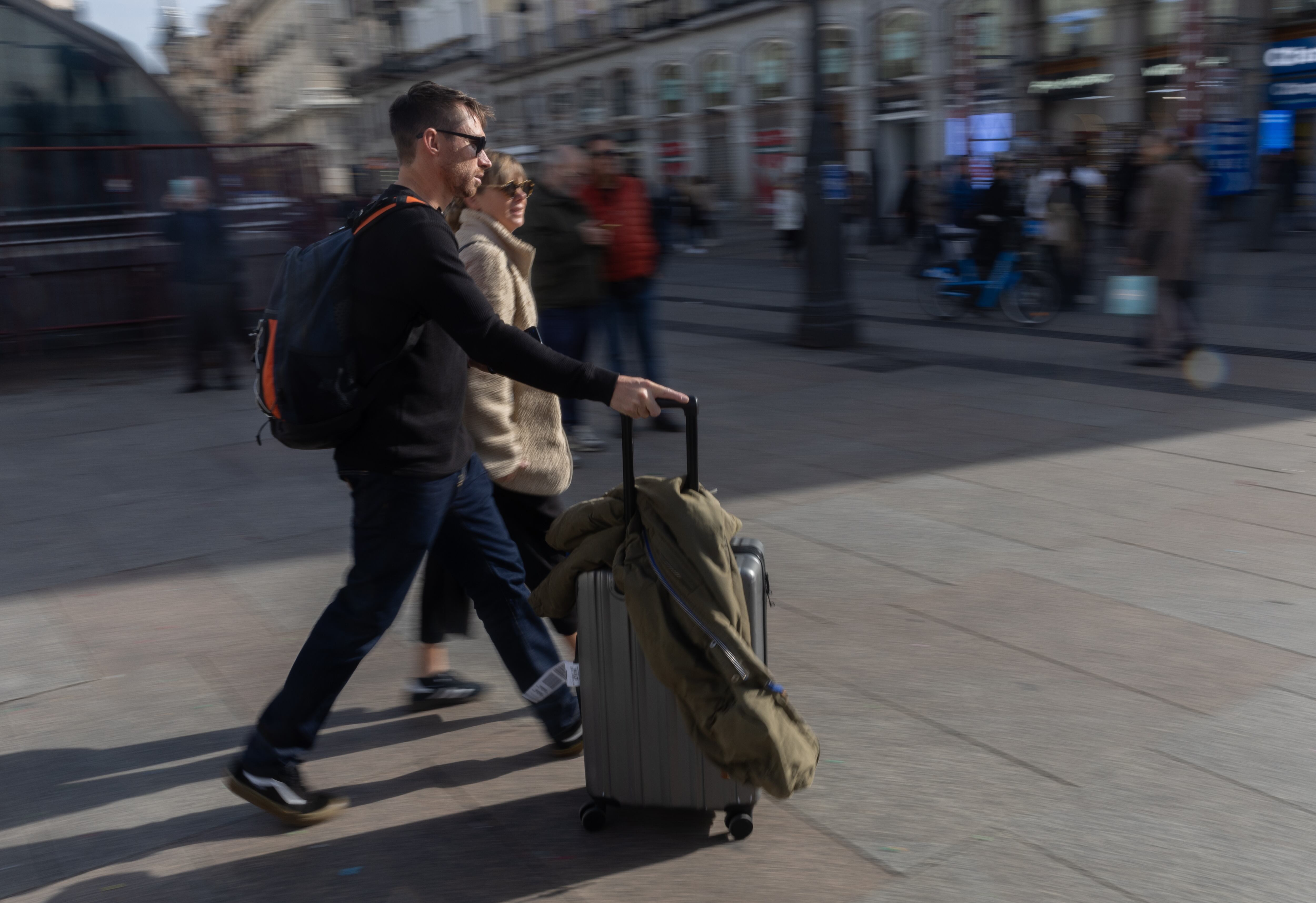 Pareja de turistas caminando en un área urbana con una maleta, reflejando la tendencia hacia un turismo europeo más sostenible y consciente.