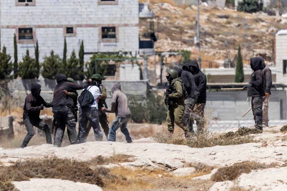Colonos israelíes, algunos con palos, se enfrentan con activistas de izquierda mientras soldados israelíes intervienen en un puesto de avanzada ubicado en la aldea palestina de Jannatah, ocupada por Israel, al sur de la ciudad de Belén, el 25 de agosto de 2026.