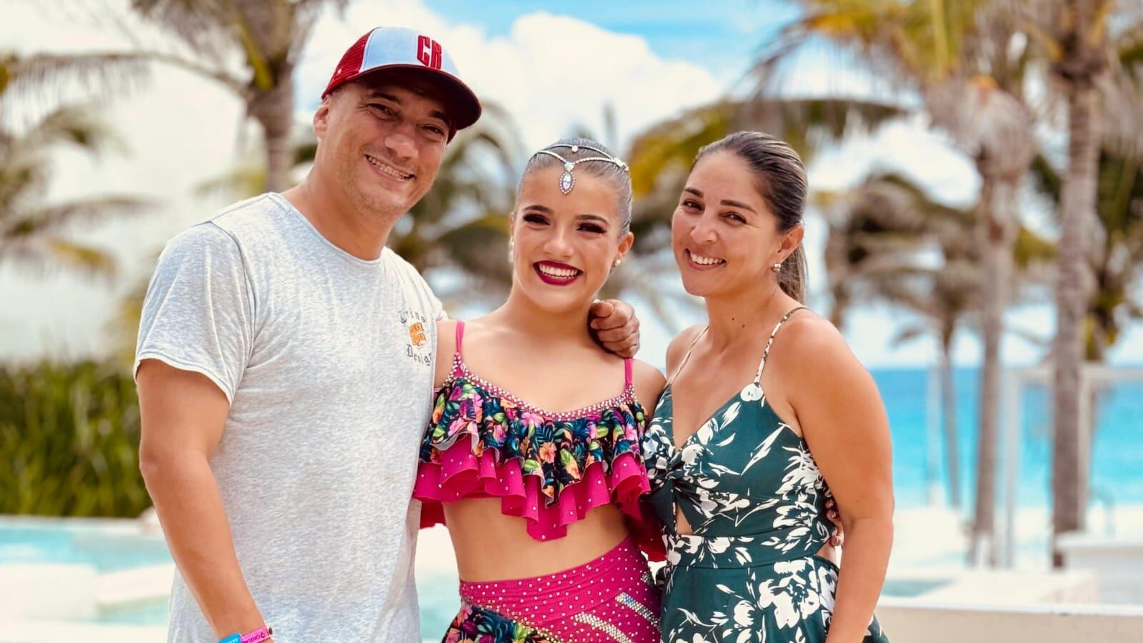 Imagen del cantante costarricense Tapón junto a su hija Mariangel Gómez y su esposa Marianné Vargas. La joven viste su traje de competencia de baile, mientras que el cantante usa camisa blanca y gorra, la esposa tiene un vestido de color azul.