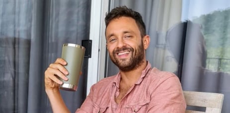 Renzo Rímolo, comediante costarricense, sonriente y con una taza en mano, reflexiona sobre sus Navidades infantiles llenas de unión familiar.