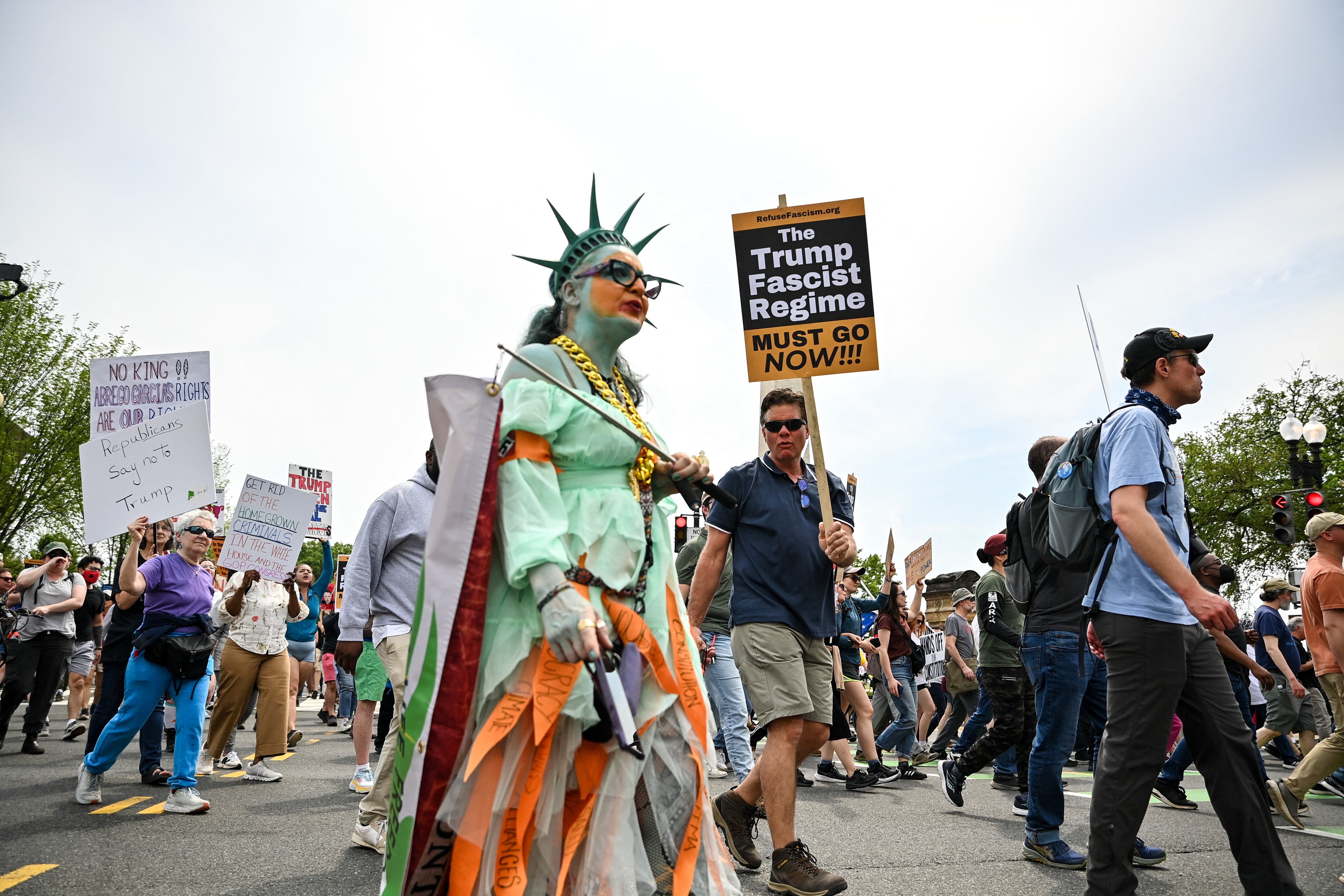 Protestors hold signs as they march towards the White House during a Free Kilmar Abrego and an Anti-Trump protest, in Washington, DC, April 19, 2025. Abrego Garcia was detained in Maryland last month and expelled to El Salvador along with 238 Venezuelans and 22 fellow Salvadorans who were deported shortly after President Donald Trump invoked a rarely-used wartime authority.