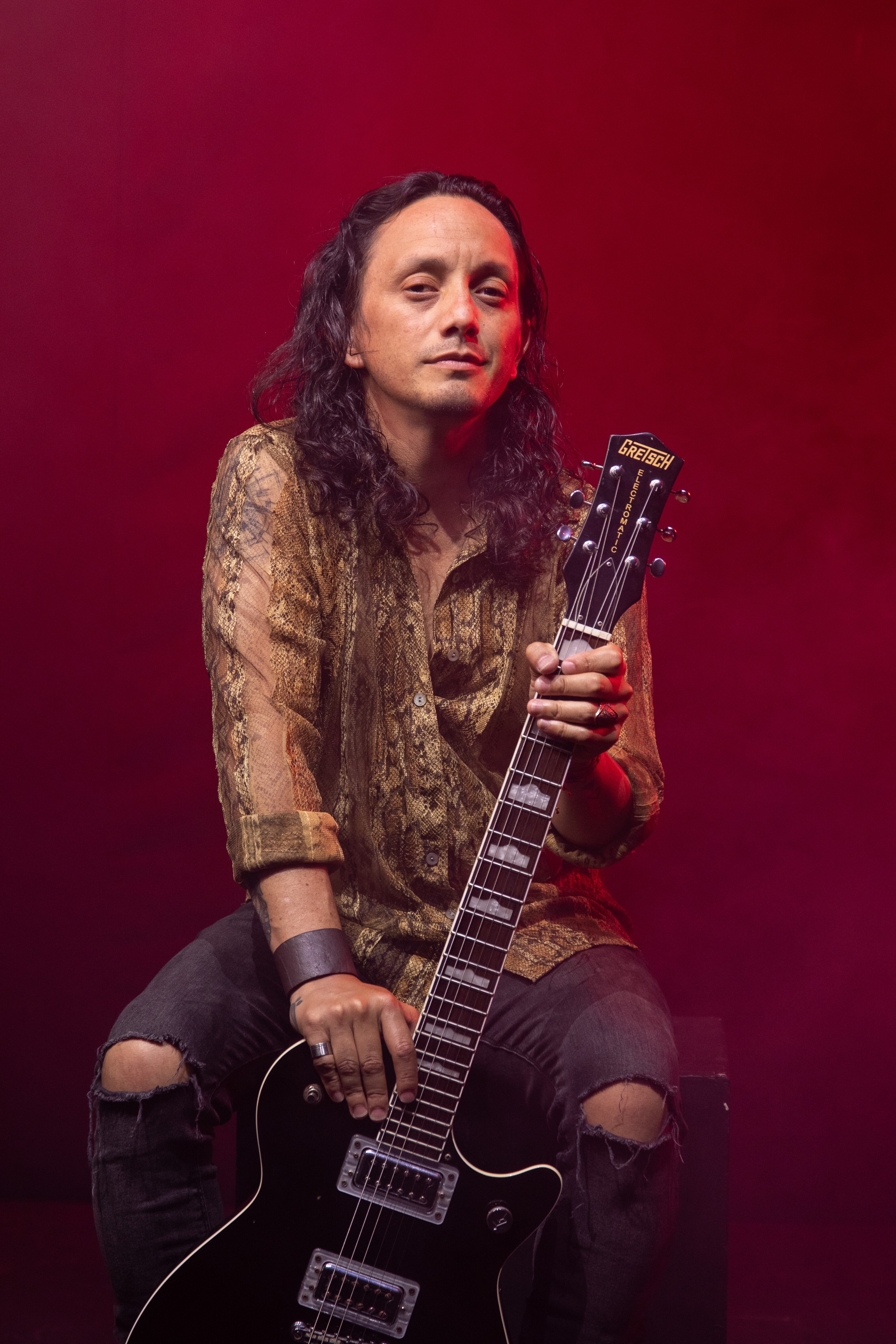 Imagen del músico costarricense Ed Quesada sentado en una silla y con una guitarra en la mano.