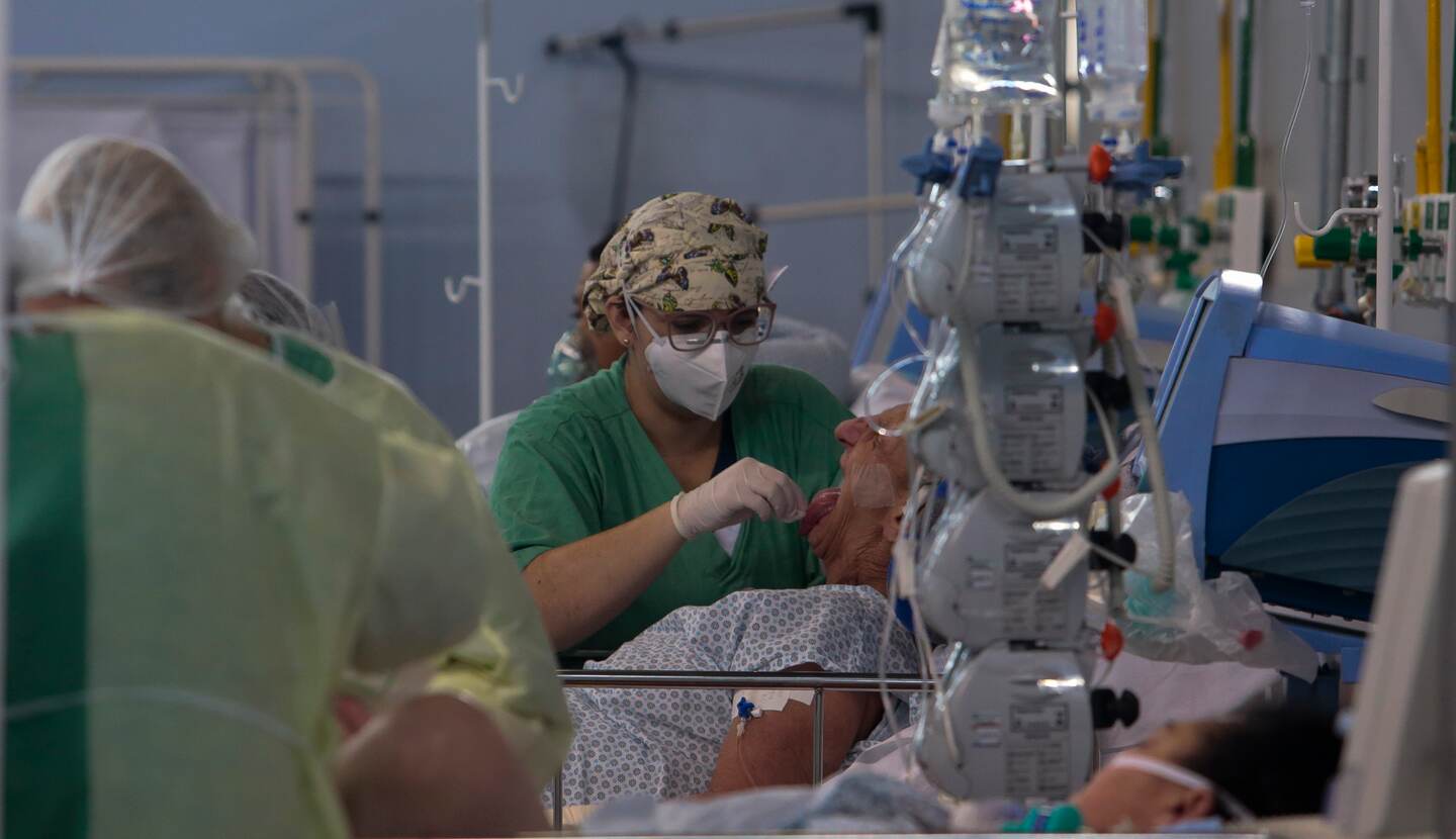 A patient affected by the COVID-19 coronavirus is treated at a field hospital set up at a sports gym, in Santo Andre, Sao Paulo state, Brazil, on May 11, 2020. (Photo by Miguel SCHINCARIOL / AFP)